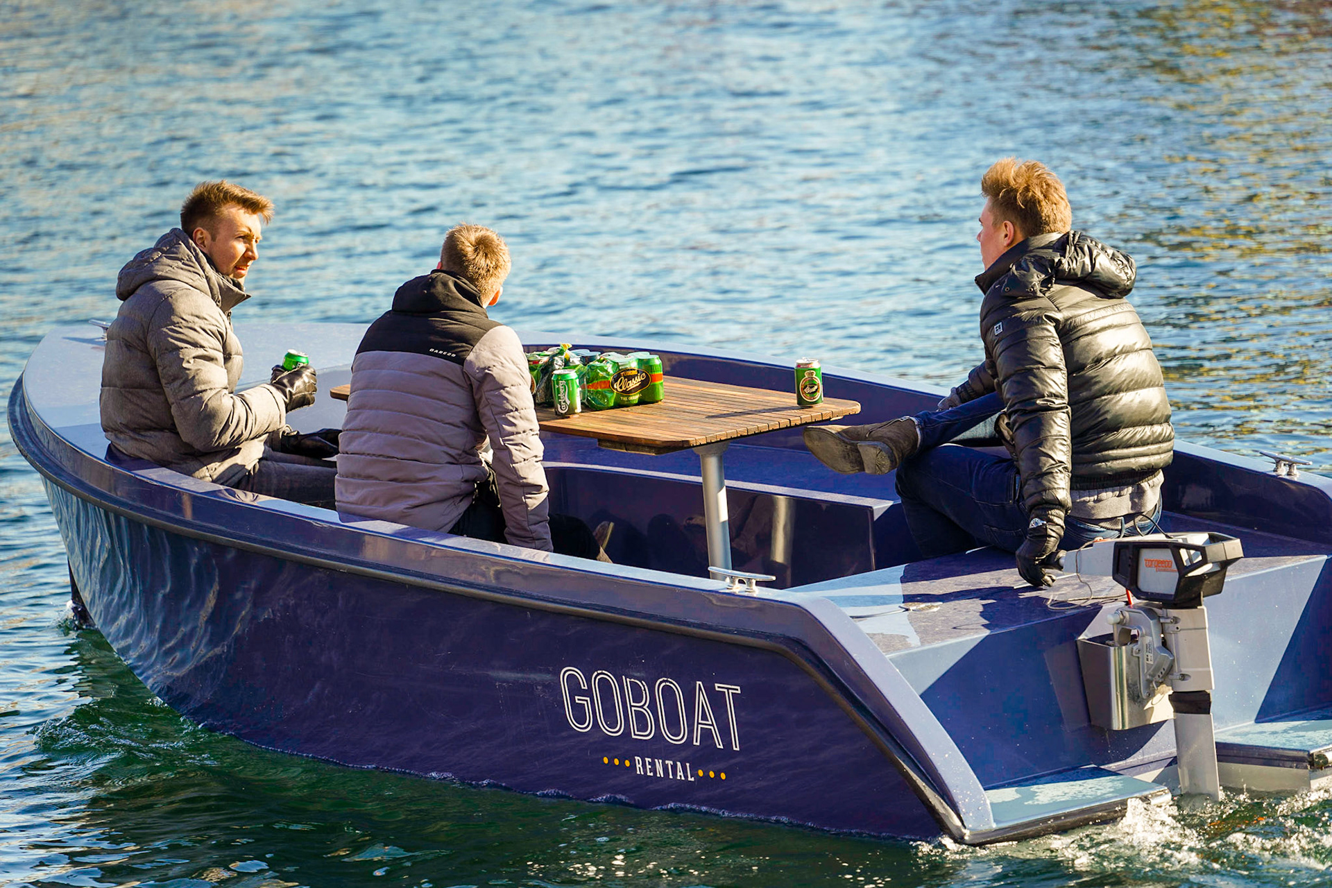 Three men on a boat in a Canal in Copenhagen, Denmark, relaxing, having Carlsberg and Tuborg Classic beer