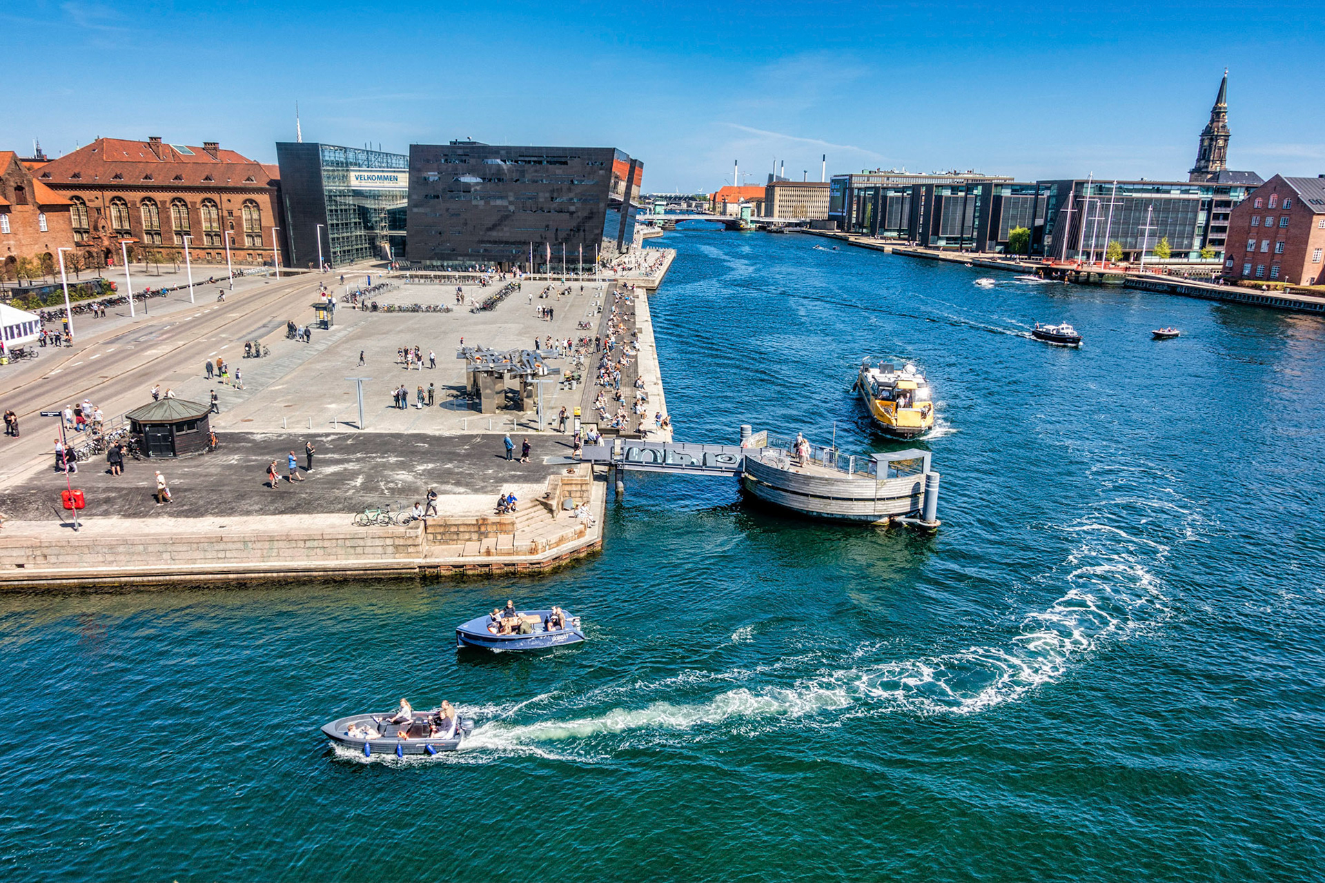 Copenhagen waterfront with The Black Diamond and Soren Kierkegaards Square, yellow water bus and boats, seen from DAC's terrace in the Blox building