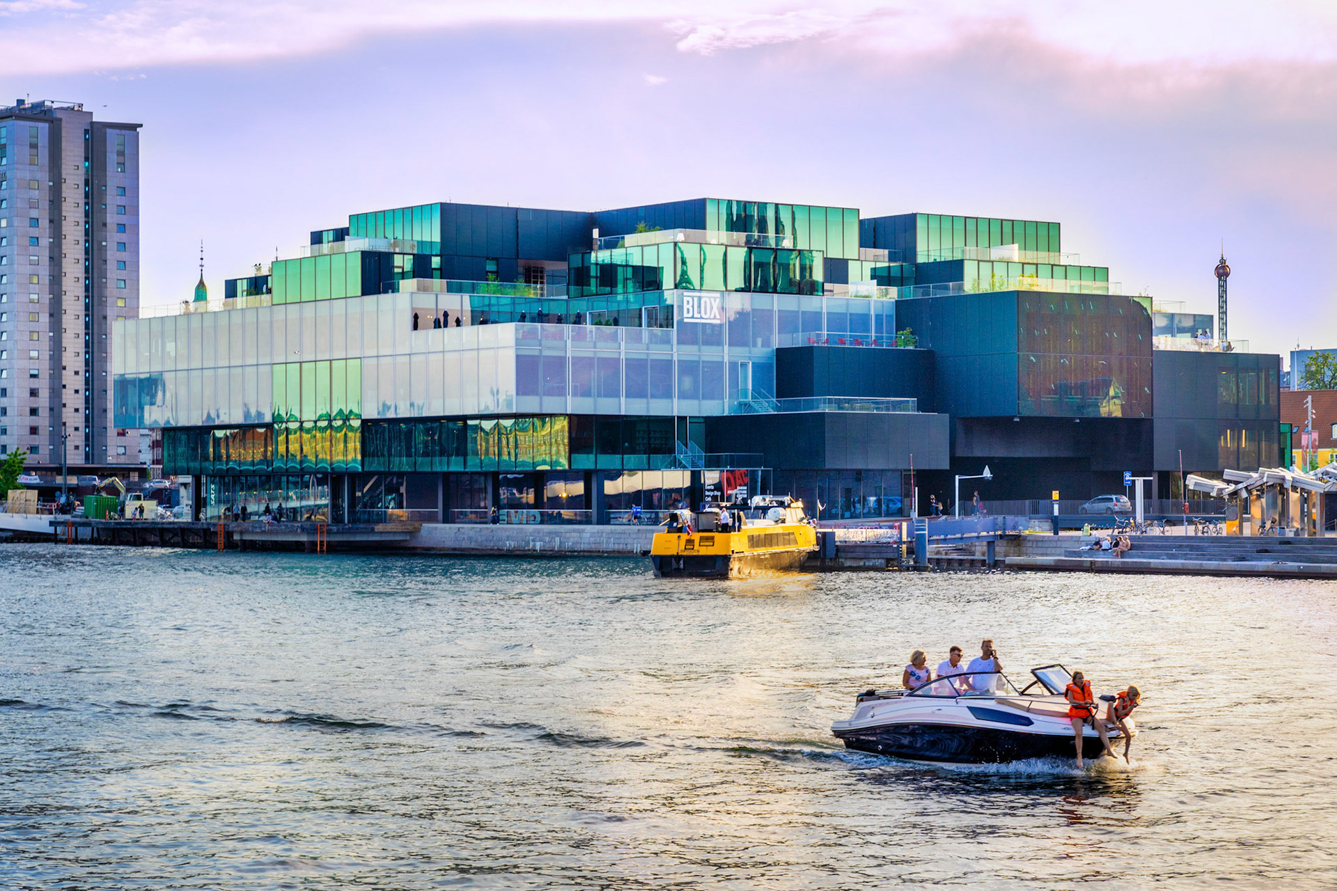 The Blox building from 2018 by the Copenhagen waterfront, domicile for DAC, Dansk Arkitektur Center. Leisure boat in front.