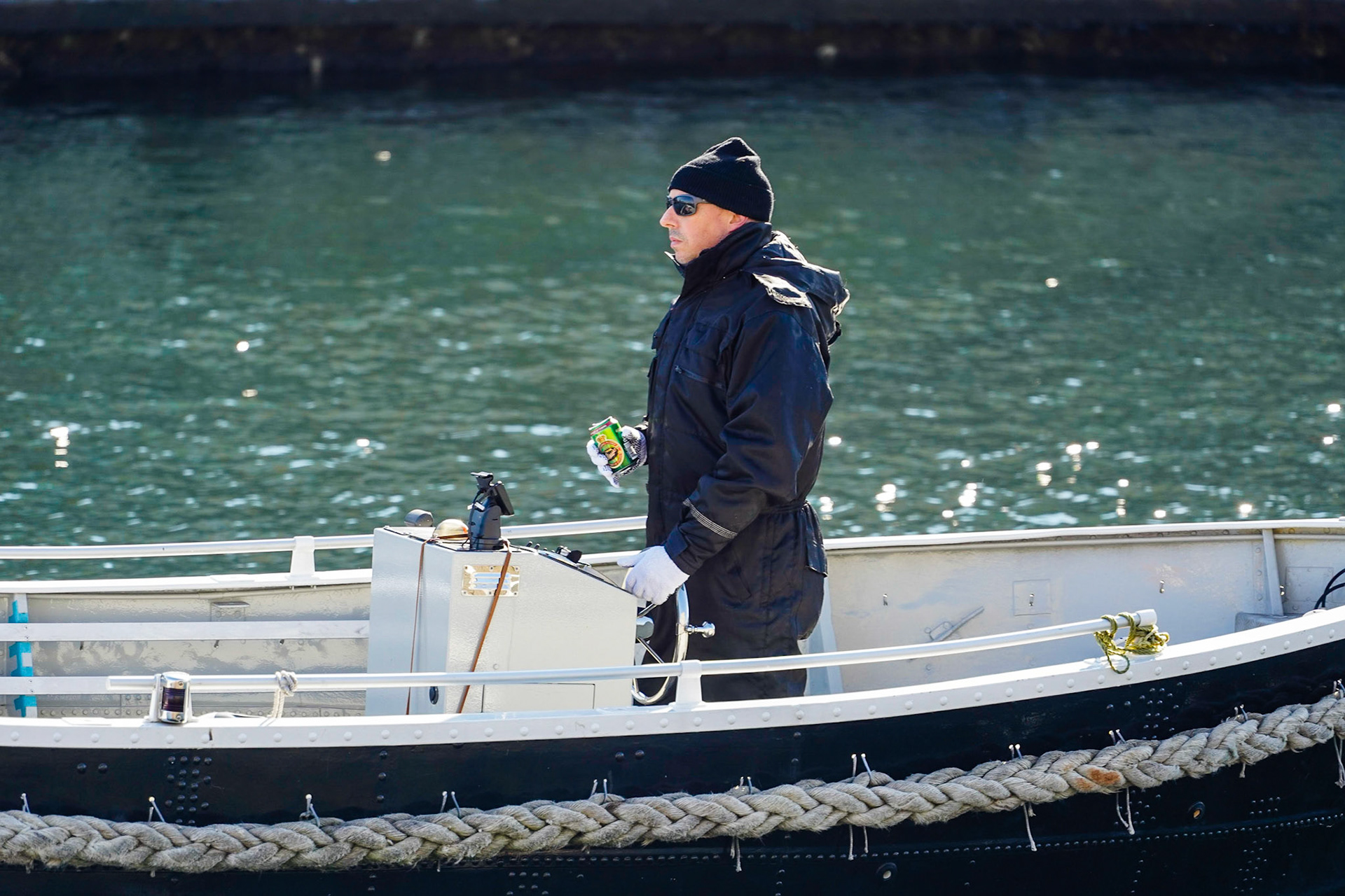 Man on a boat in a Canal in Copenhagen, Denmark, Danish flag Dannebrog, relaxing, having a Tuborg Classic beer