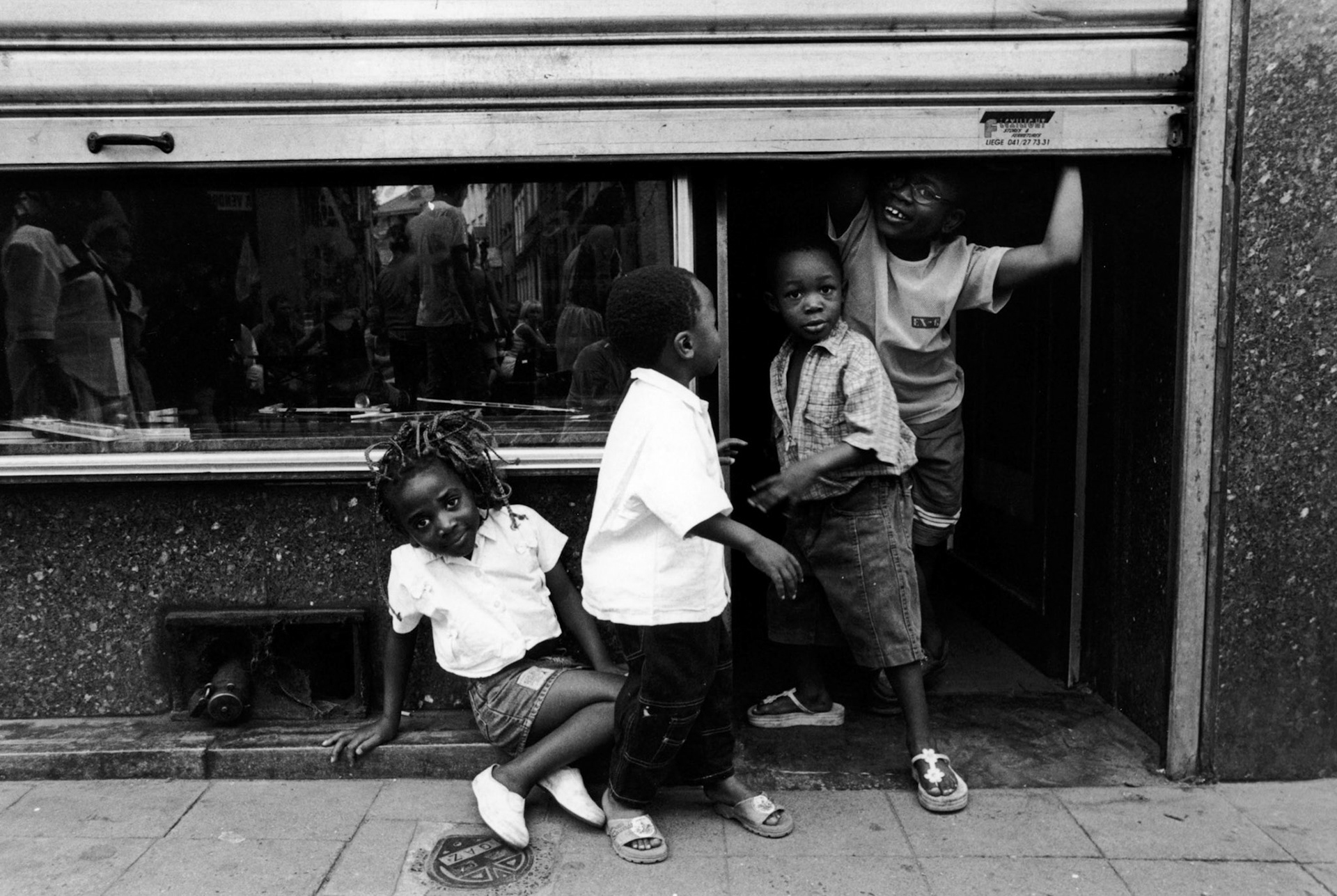 Kinderen spelen onder rolluik in de wijk Outres Meuse in Luik augustus 2001