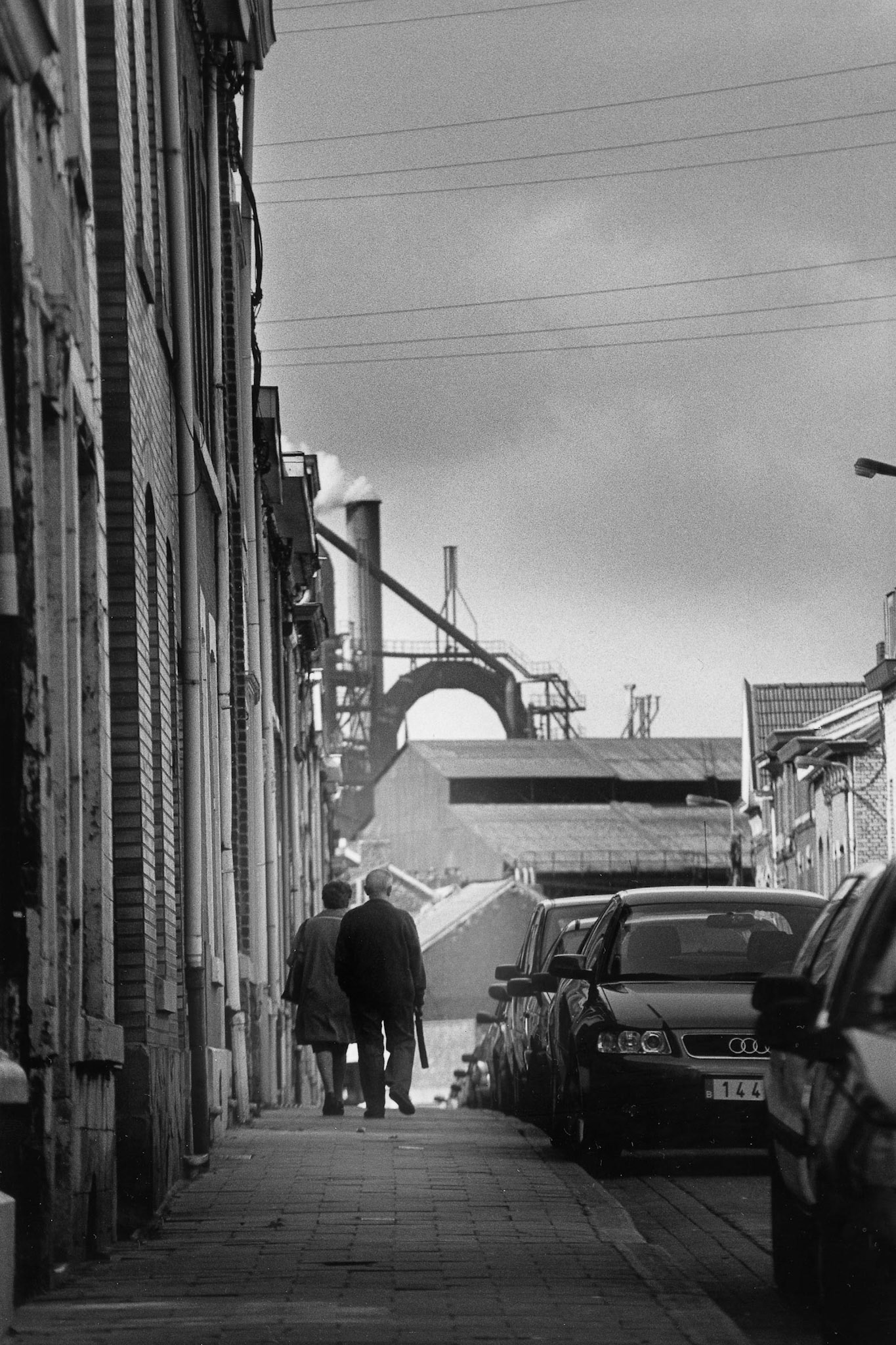 Oud koppel loopt over straat met industrie in de achtergrond. Seraing, sept. 2002
"Onder industrieele vleugels"
Maassteden in Wallonie.