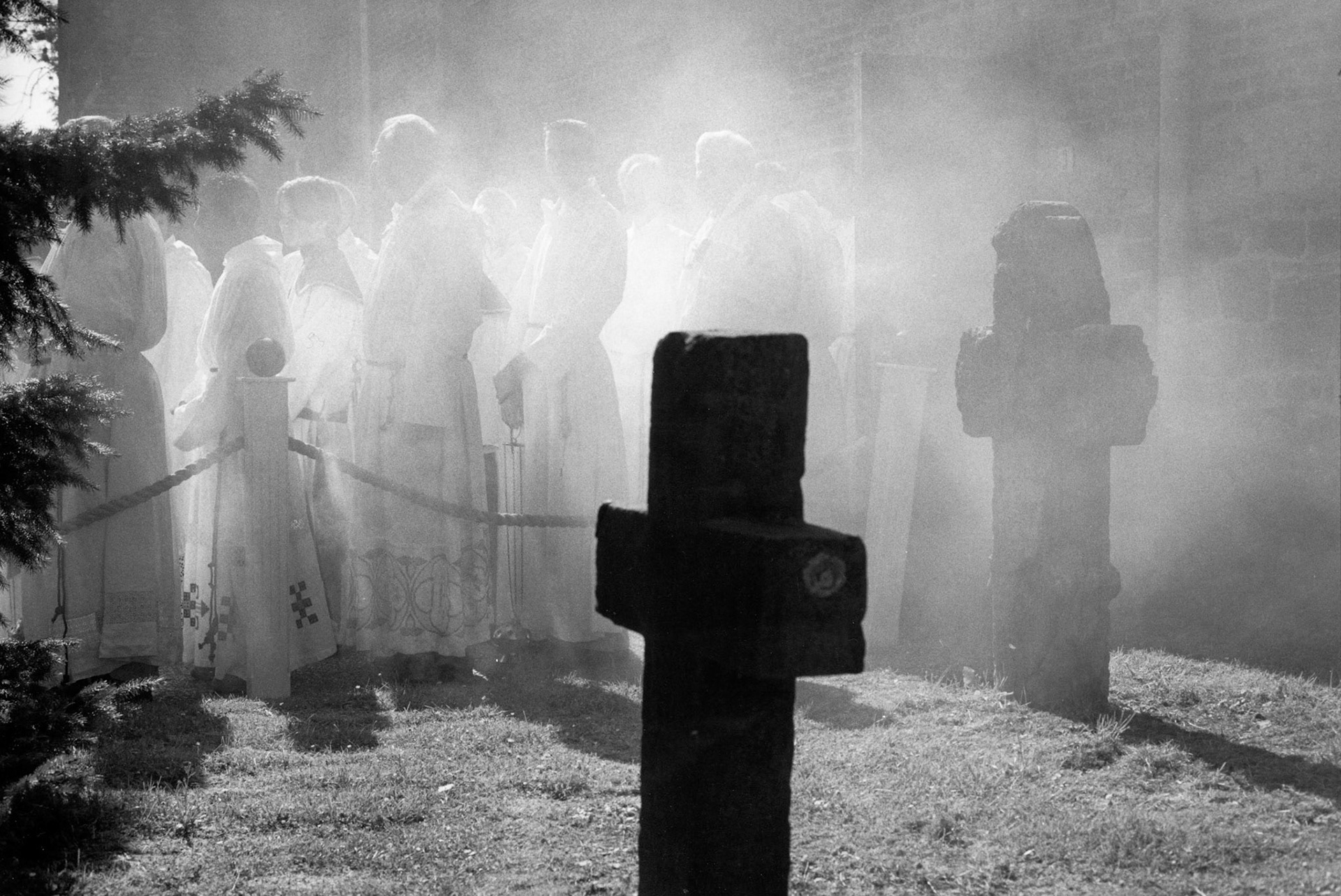 Een stoet van misdienaars verlaat de kerk langs de begraafplaats gehuld in een nevel van wierook tijdens de "Bronk" processie in Eijsden 22-6-2003