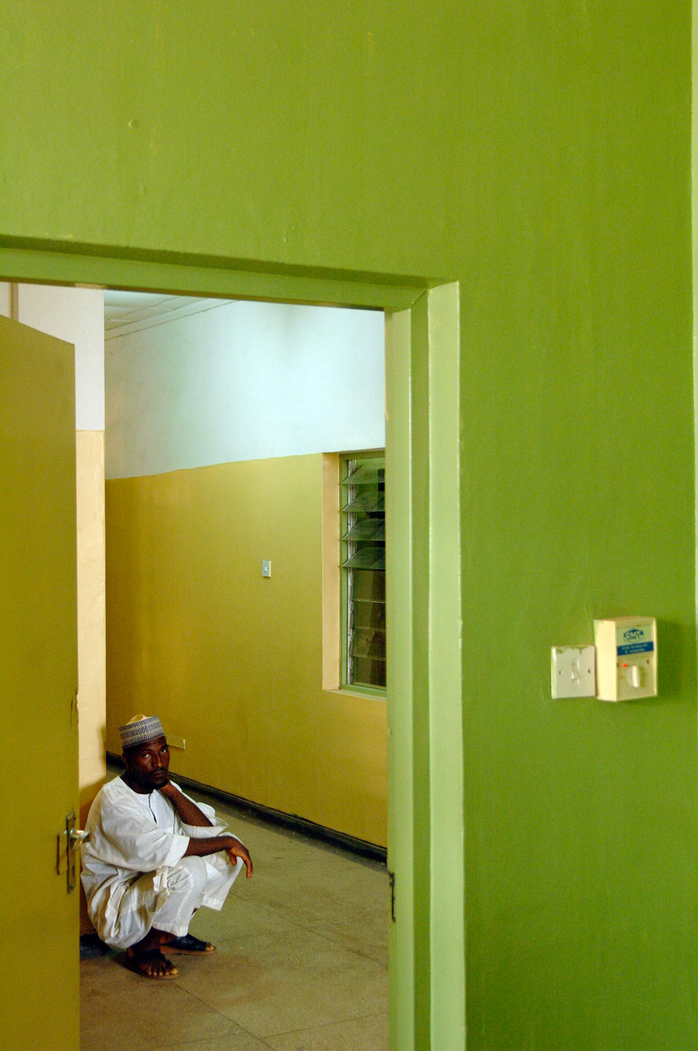 Man wacht gehurkt op gang in Kaduna hospital, Nigeria 4 april 2006