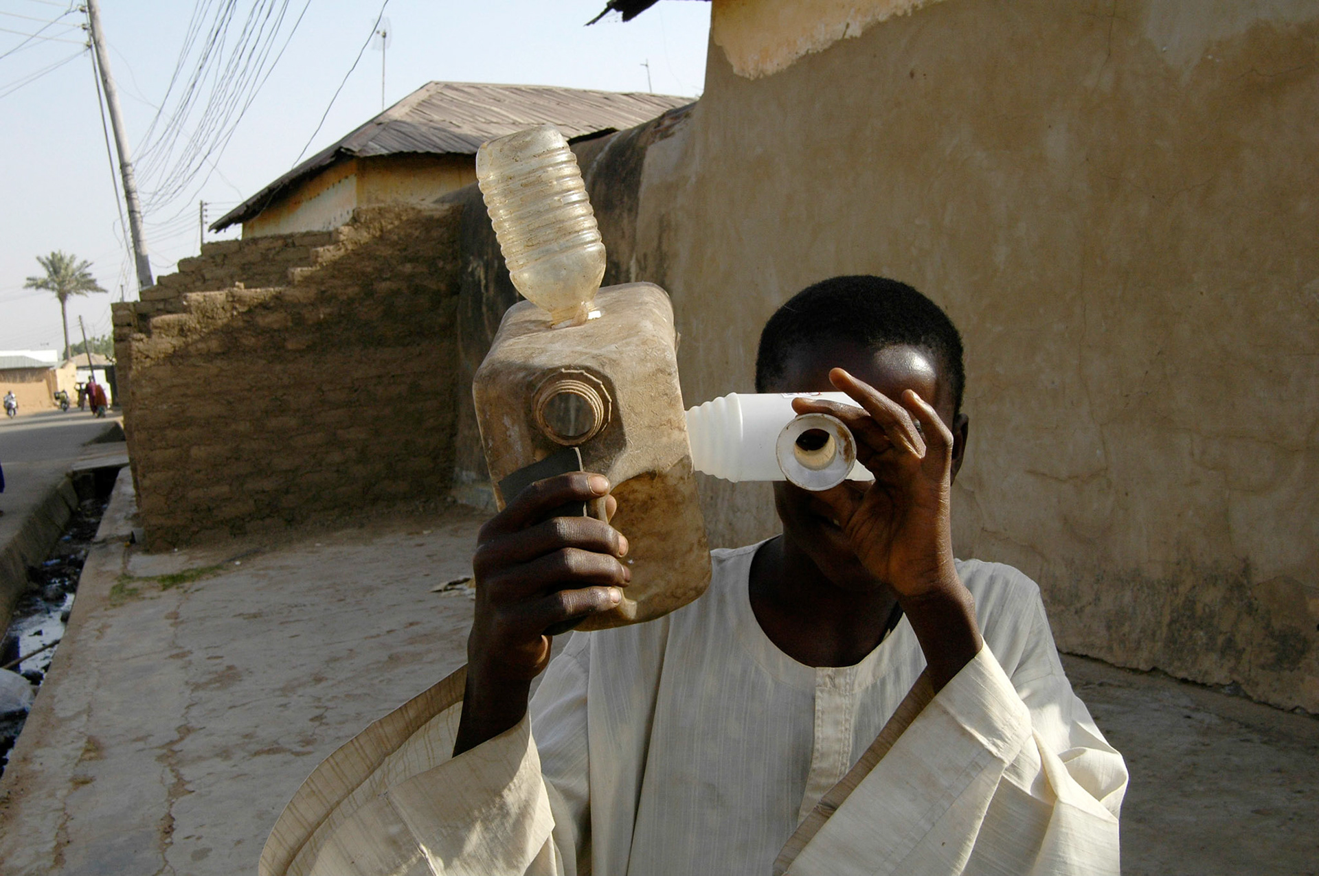 Met een grote lach op zijn gezicht, filmt deze inventieve jonge man ons met zijn zelfgemaakte camera. Hij verdween net zo snel als hij was aangekomen. Waarschijnlijk moest hij nog een paar gekke toeristen vastleggen. Alhoewel die heel moeilijk te vinden zijn in Nigeria! Zaria 11 april  2006