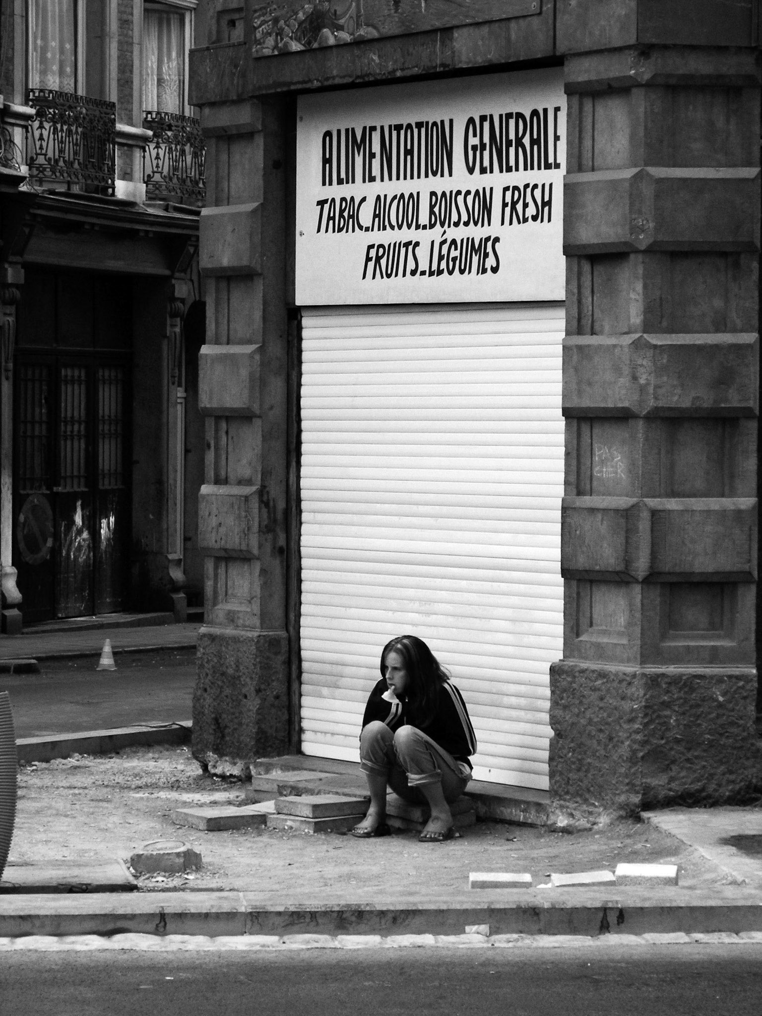 Meisje zit voor een kruidenierswinkel in Luik 3-9-2005