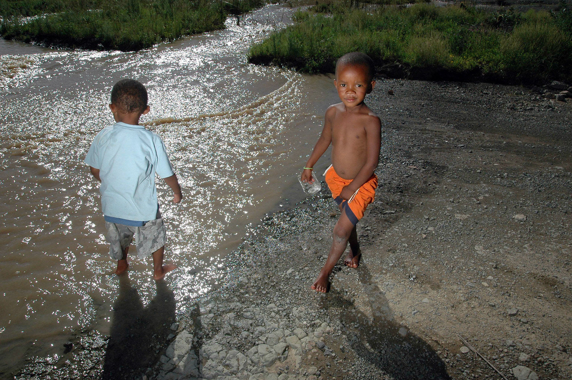 Kinderen spelen bij de overstroomde rivier van het afgelegen Nieu-Bethesda, Zuid-Afrika 15-1-2008