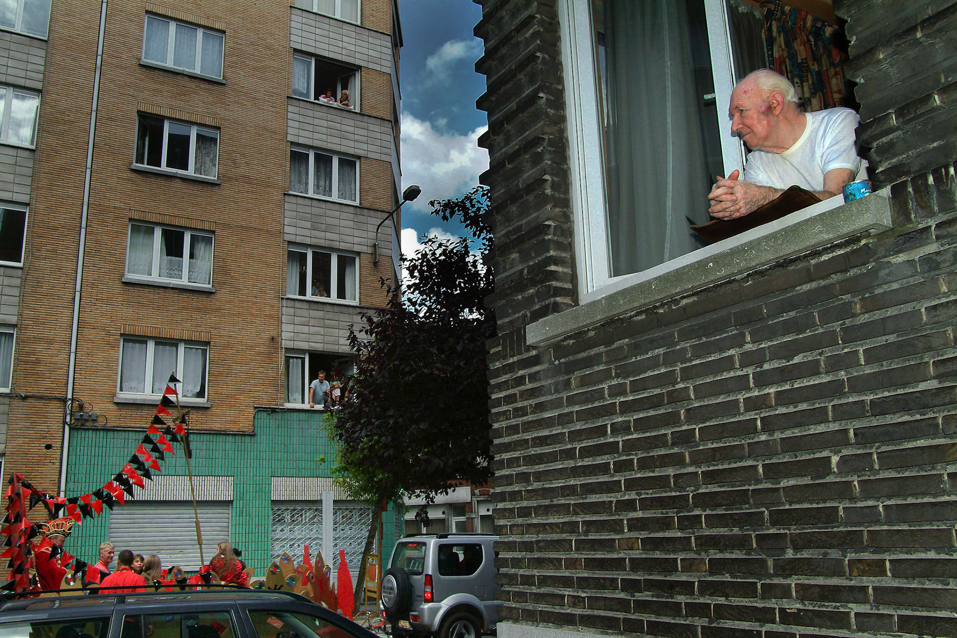 Oude man kijkt vanuit raam naar de langstrekkende optocht van het Saint Marie Festival in Luik, 15-8-2004