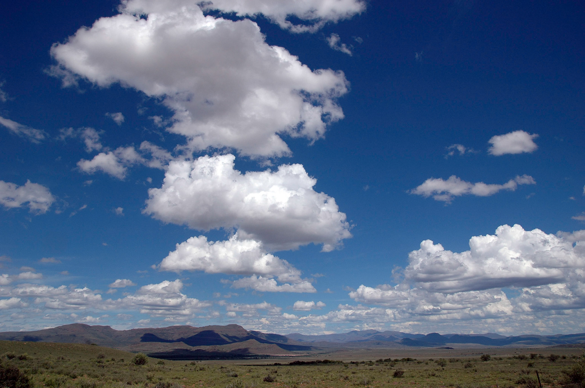 Landschap met wolken en blauwe lucht op de onverharde weg naar Nieu-Bethesda in Zuid-Afrika, 15-1-2008
