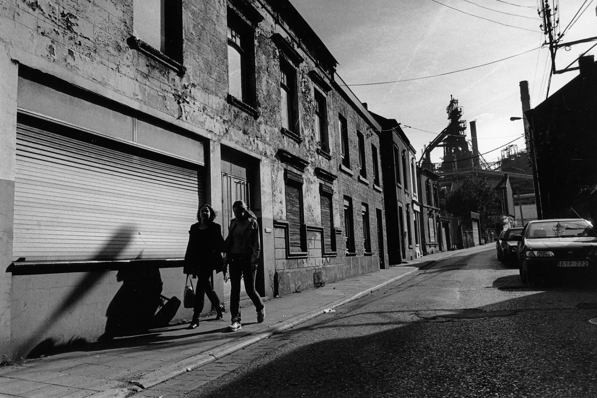 Straatbeeld van Seraing met fabriek (Cockeril Sambre) in de achtergrond, Seraing, nov. 2002. "Onder industrieele vleugels" Maassteden in Wallonie.