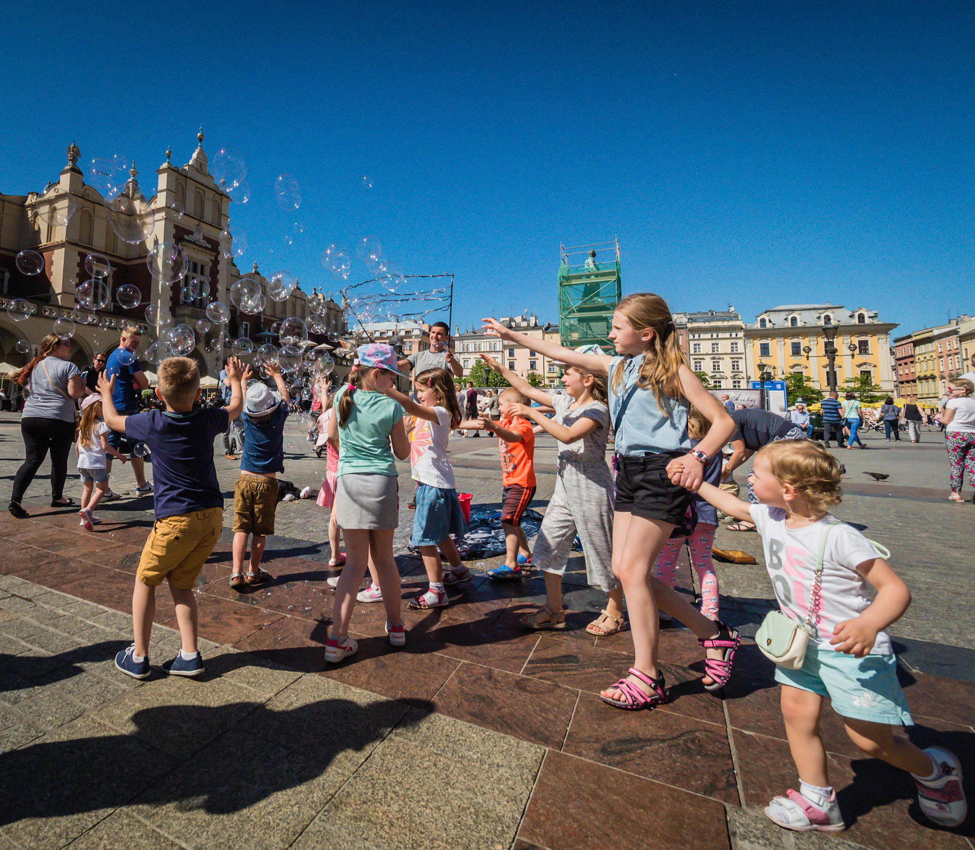 In the square in Krakow, a man was making bubble for kids to chase.  I particularly like this photo because the older sister is holder her younger sister's hand.  