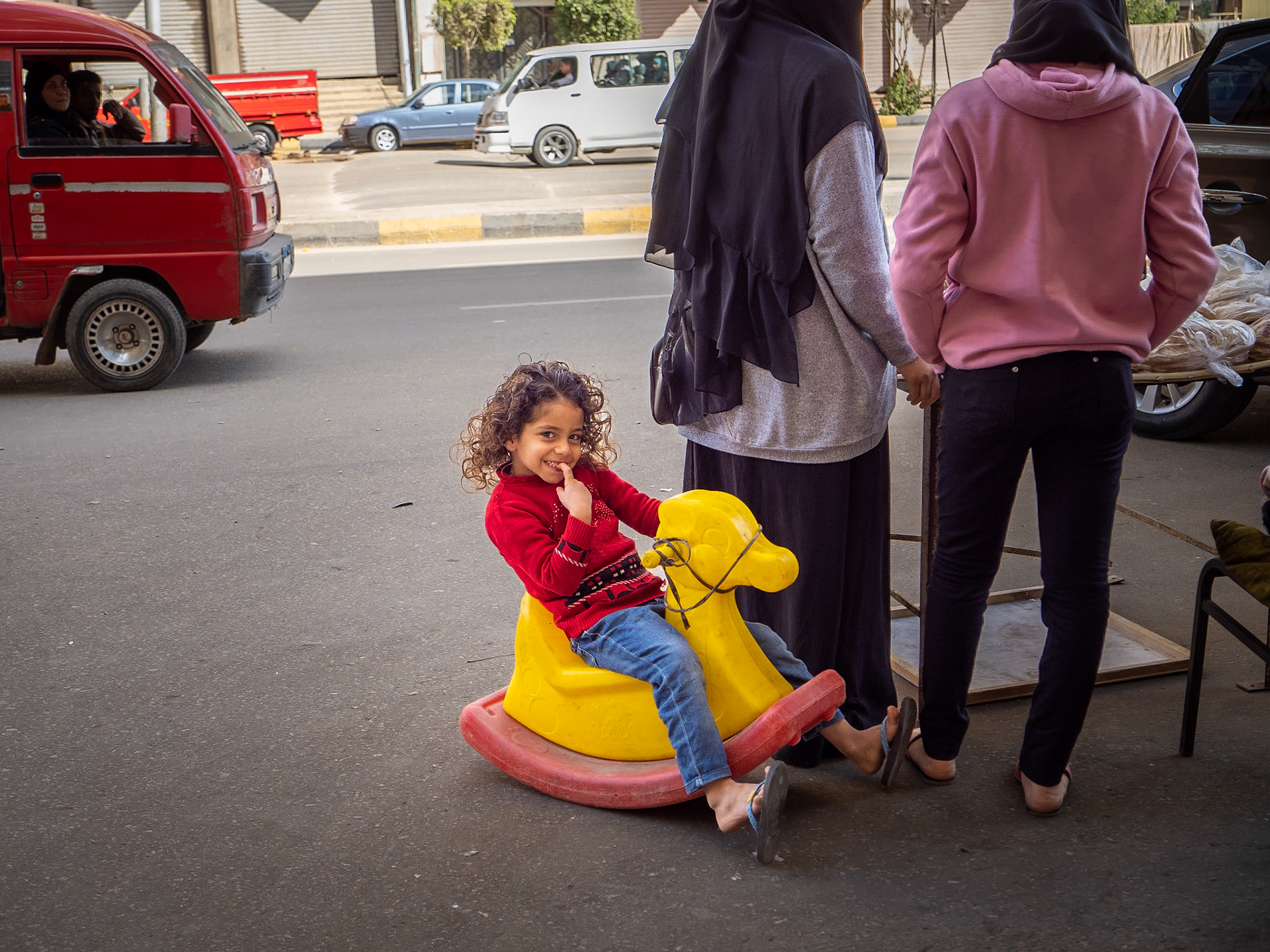 A young girl playing as her mother sold bread on the street.