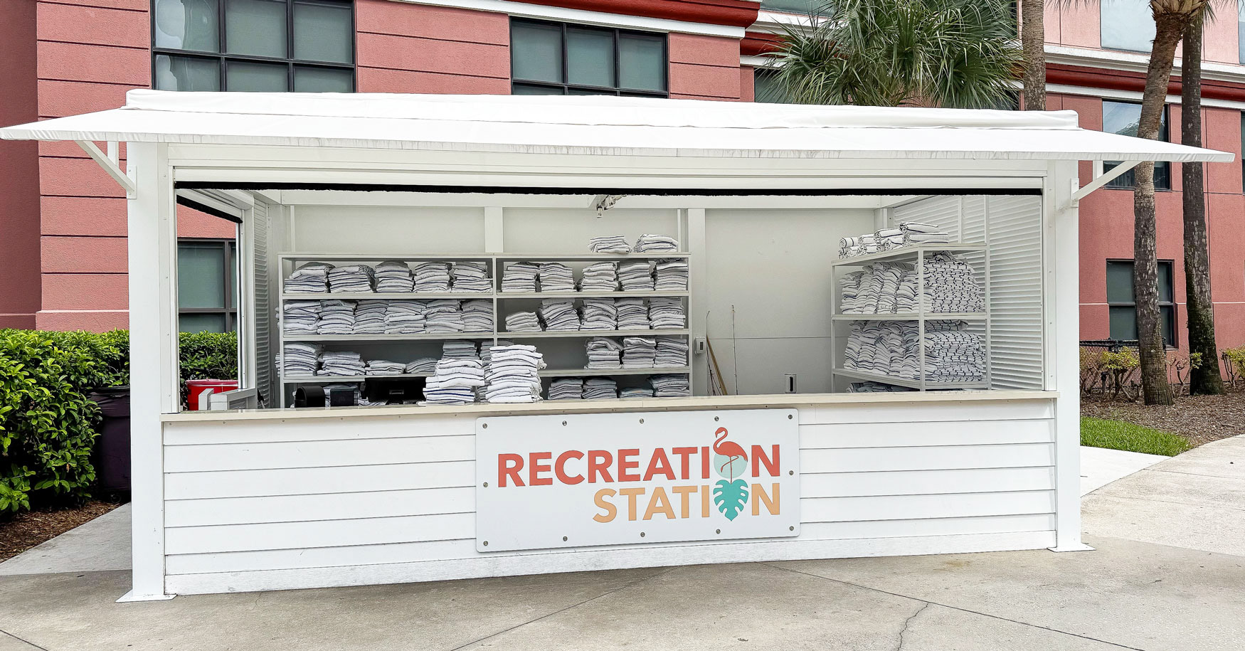 Wood hotel cabana building for towels with a large sign that says Recreation Station.