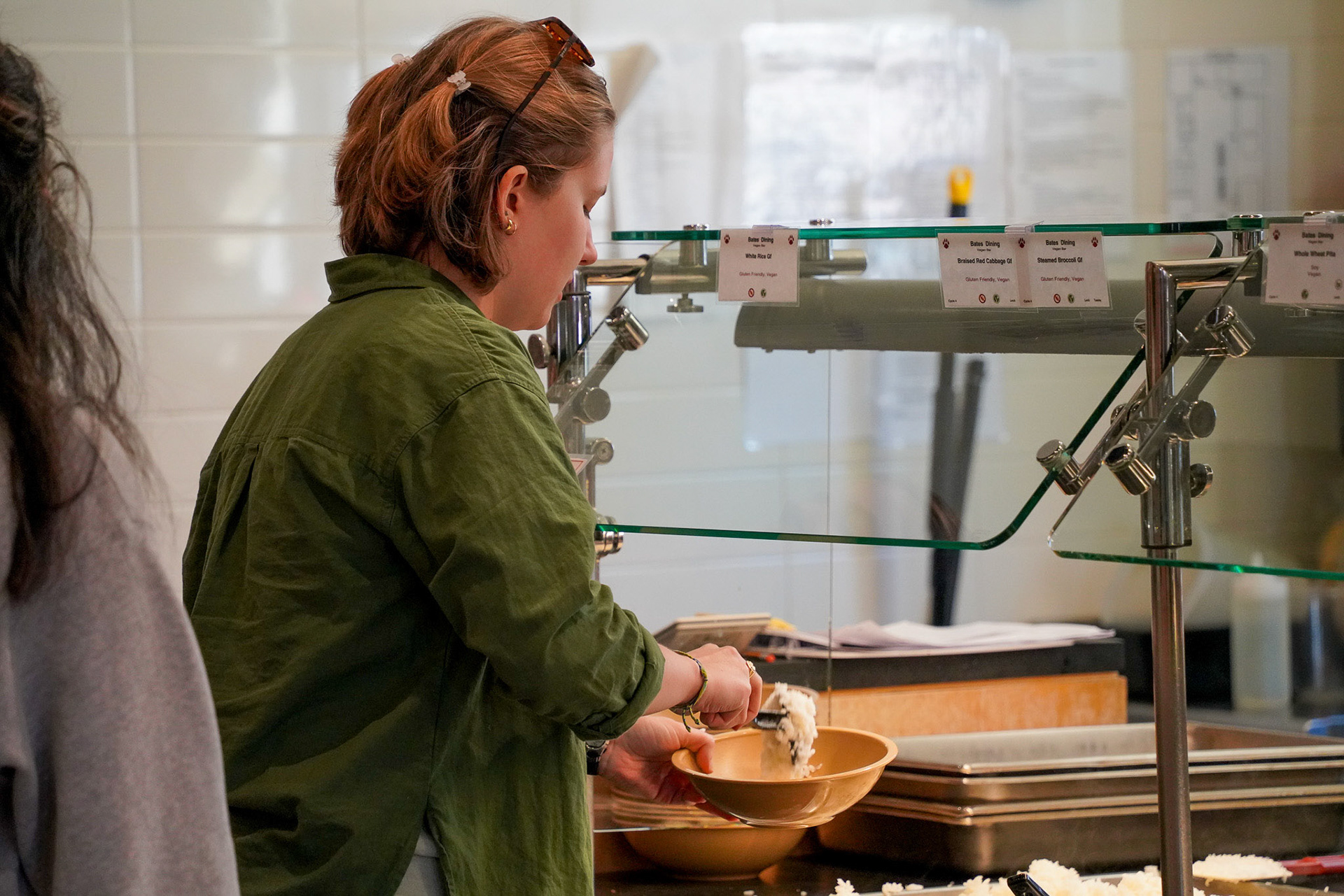 A student begins to create a bowl at the vegan bar with a white rice base.