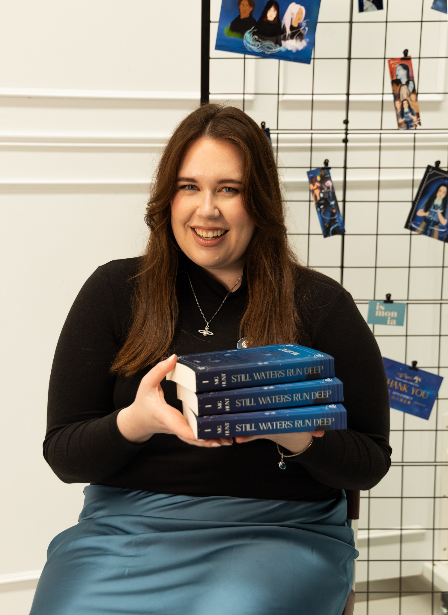 Portrait of MG Hunt holding a stack of 3 Still Waters Run Deep books.