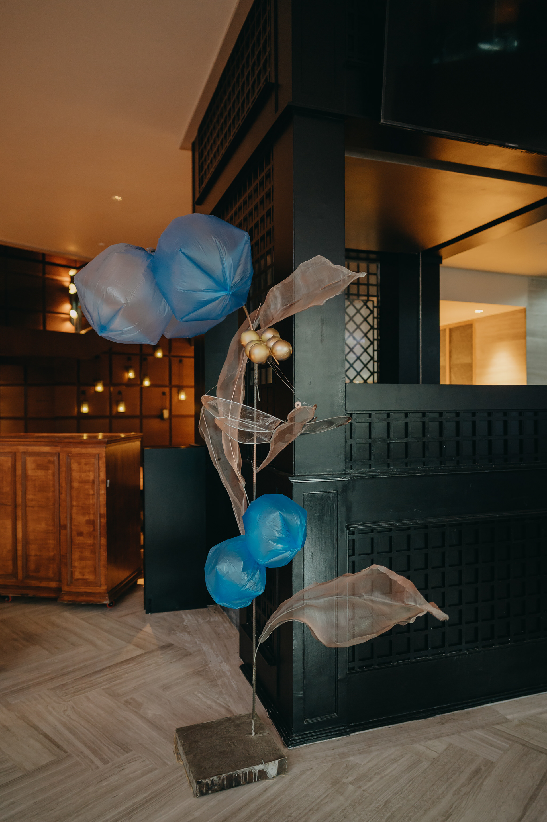 To capture the party feeling of balloons, inflated biodegradable garbage bags were arranged in the shape of flower petals, to bring a weightless, airy feeling. Contrastingly, the leaves were made of wire mesh cut and twisted into organic shapes, and painted in different metallic shades that would catch the light.