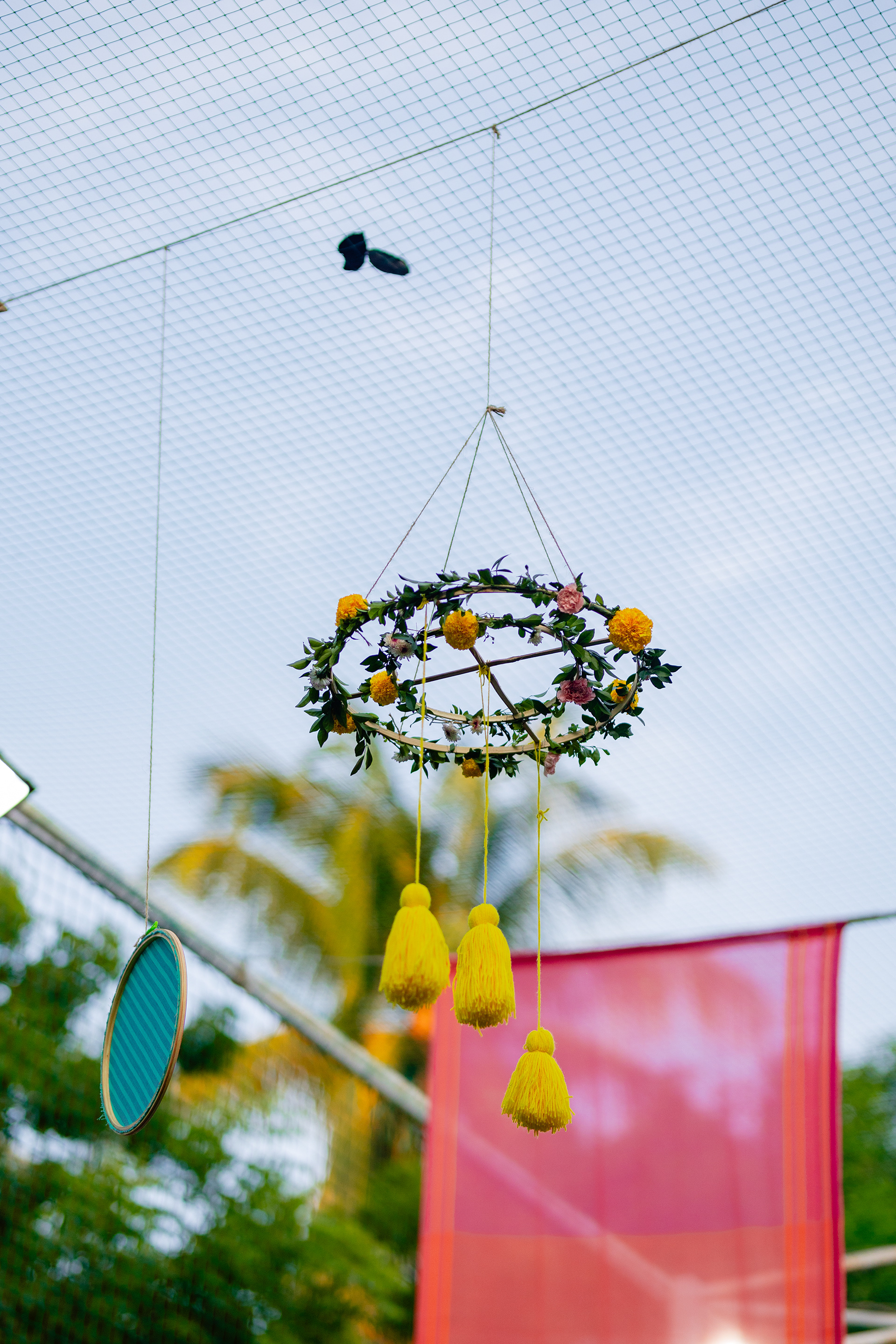 The ceiling was filled with whimsical hanging decor details, like more fabric frames, embroidery hoops with gauzy fabric and leafy chandeliers with popping yellow tassels.