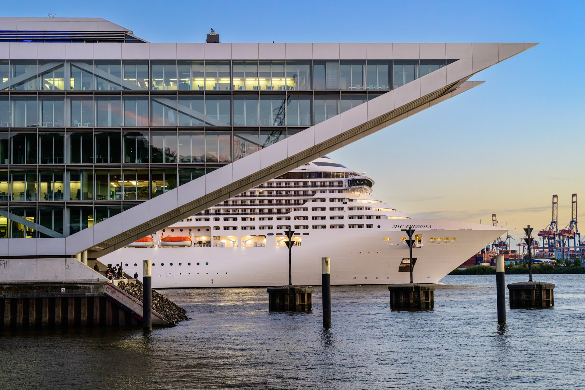 Das Dockland ist ein 2006 eröffnetes Bürogebäude, dessen Architektur an ein Schiff erinnert. Im Hintergrund verlässt das Kreuzfahrtschiff MSC Preziosa den Hamburger Hafen.