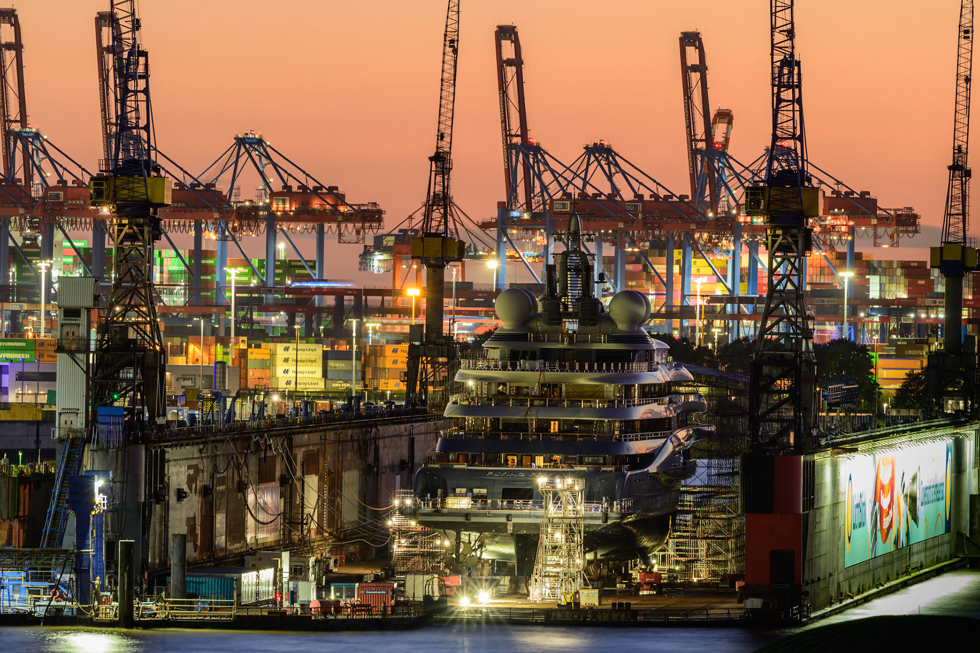 Im Dock der Blohm und Voss Werft wird Tag und Nacht gearbeitet. Im Hintergrund sind die Kräne des Containerhafens sichtbar.