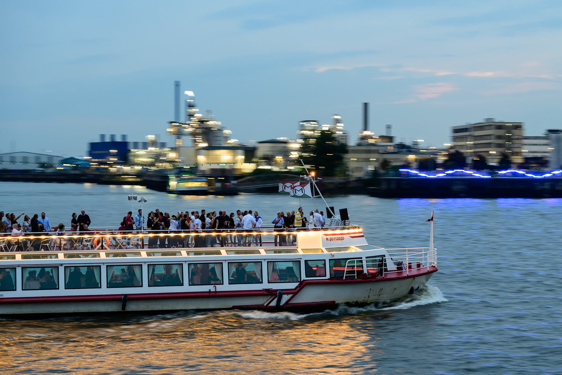 Ein Ausflugsboot fährt in der Abenddämmerung im Hamburger Hafen.