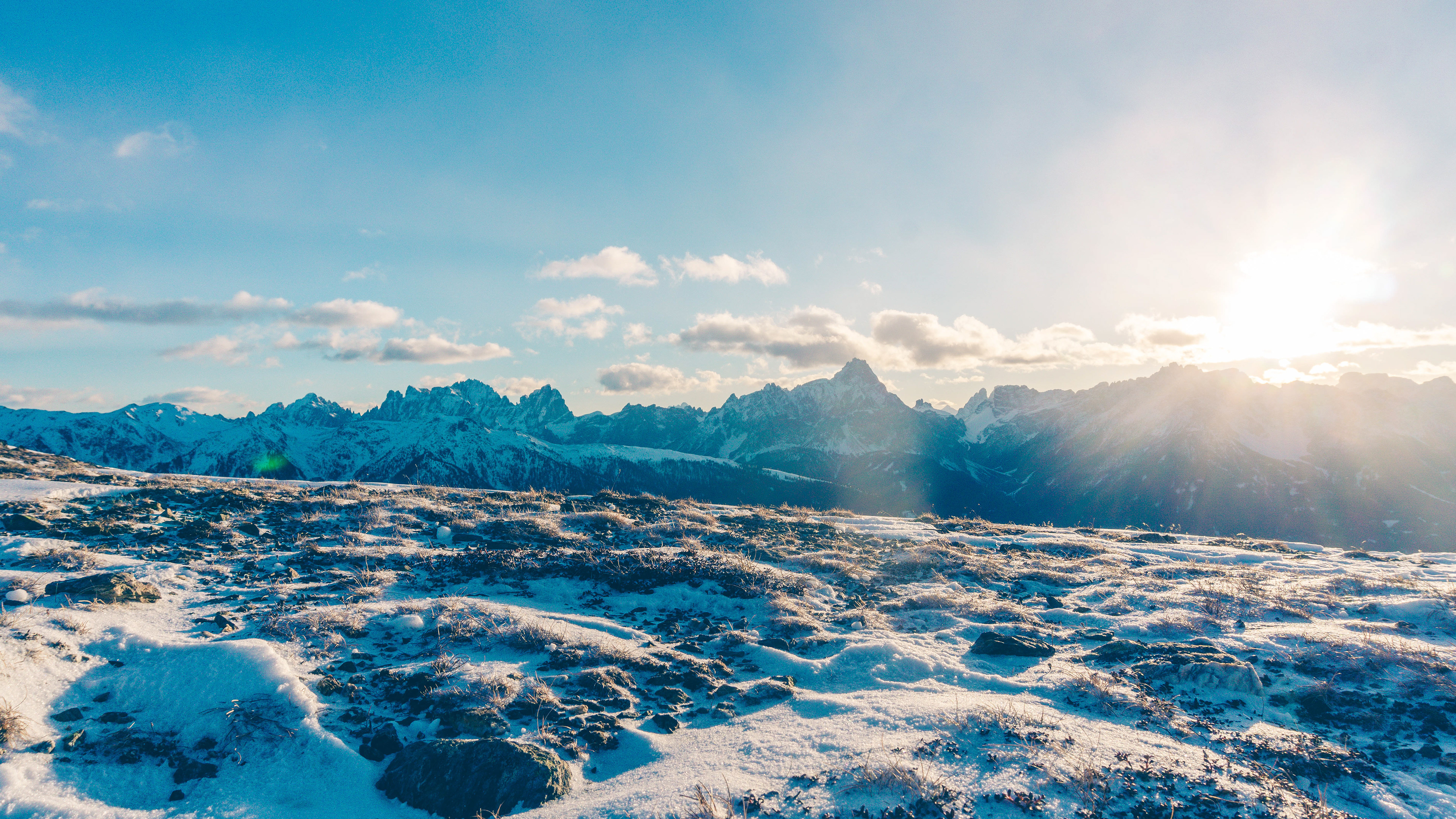 Sun setting in the snowy mountain peaks creating lens flare