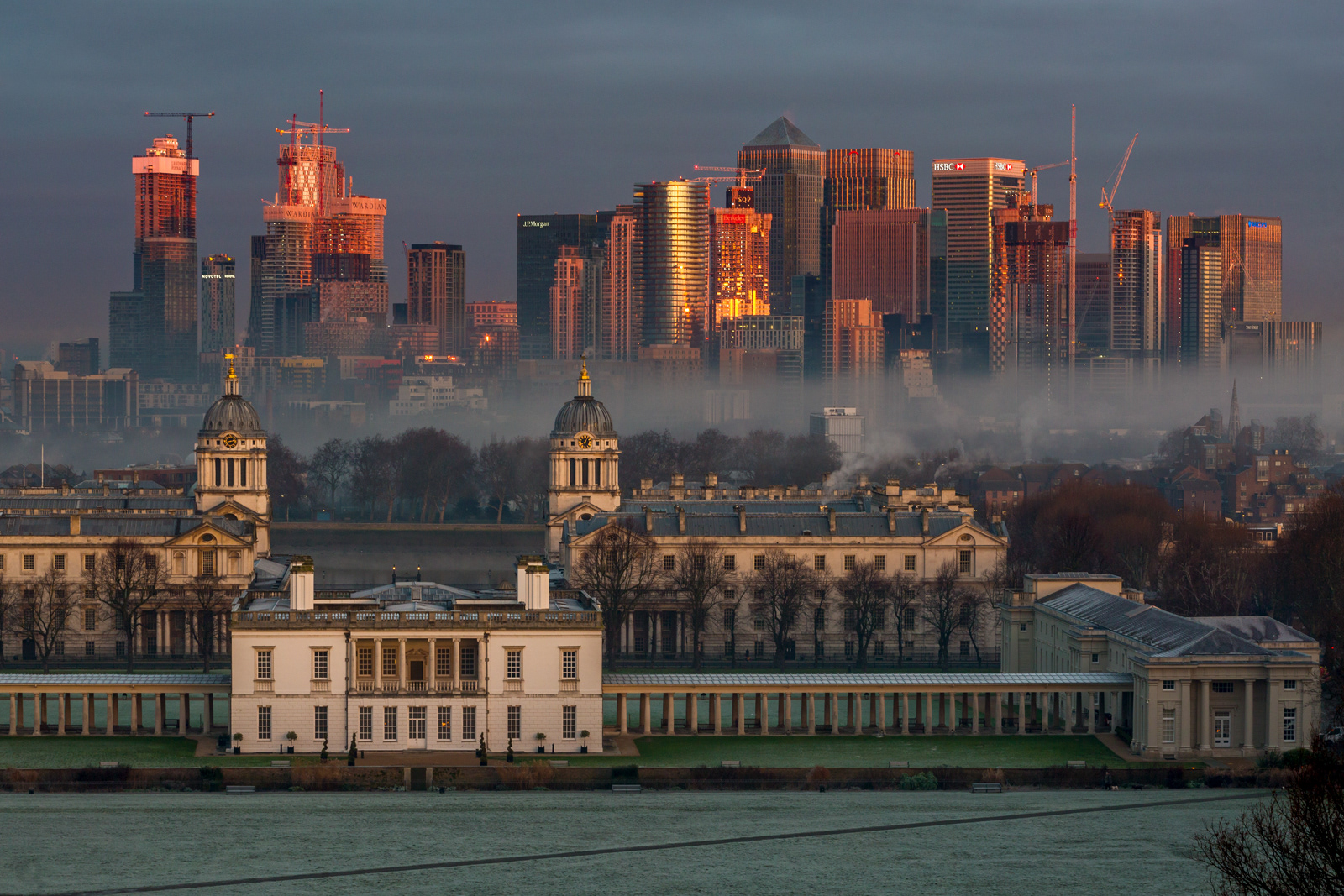 Winter morning light over the Queen's House, the Old Royal Naval College and the buildings of Canary Wharf, London, England, UK