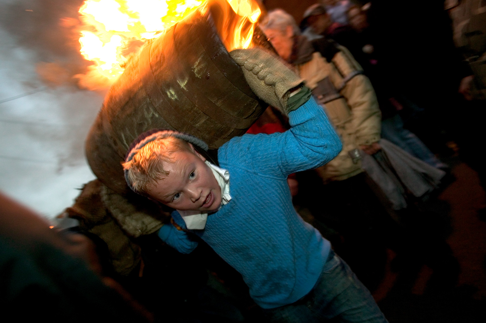 Boy carrying burning tar barrel, Ottery-St-Mary, Devon, England