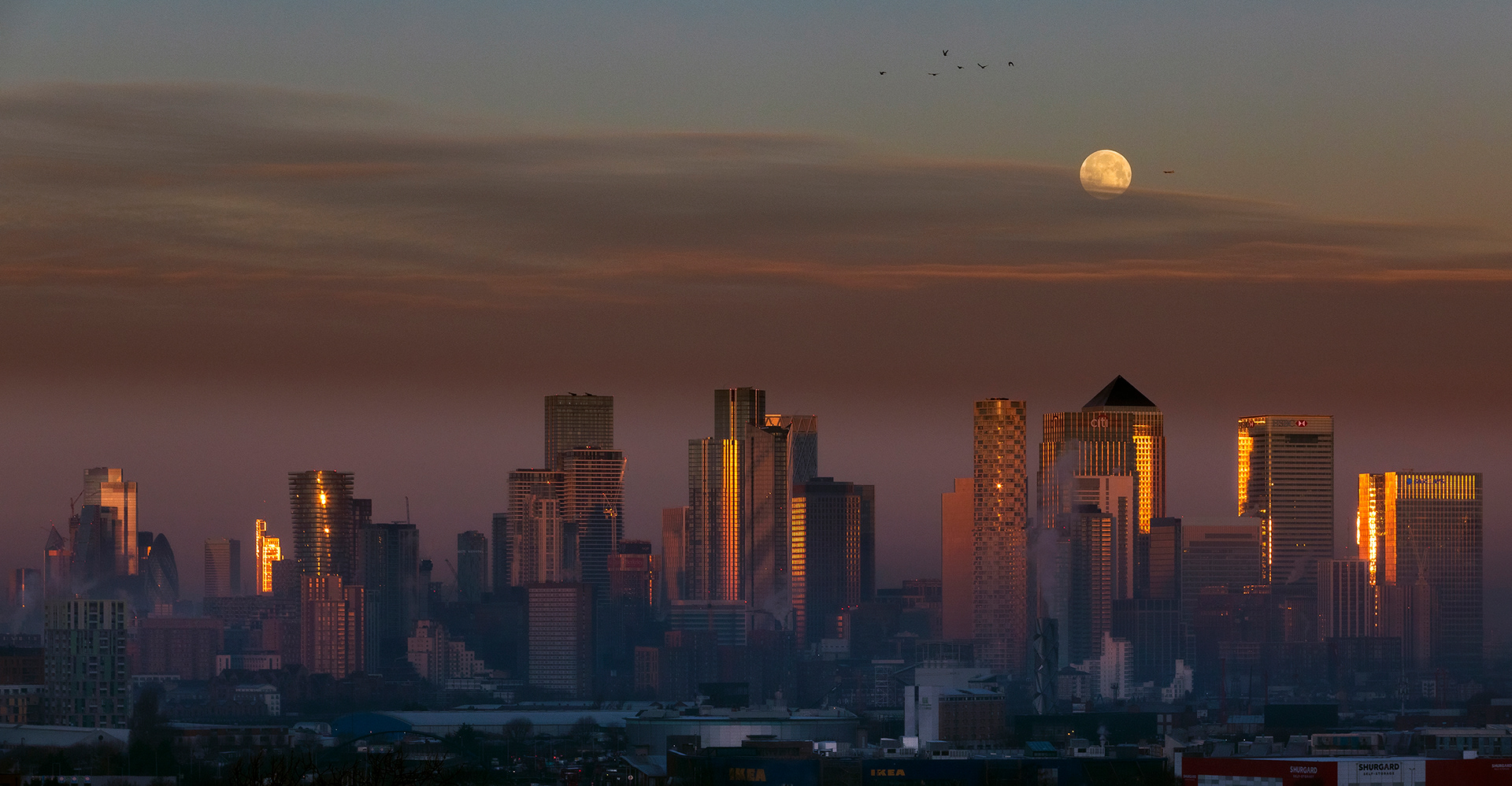 The 'Wolf Moon" setting over Canary Wharf with a winter sunrise, London