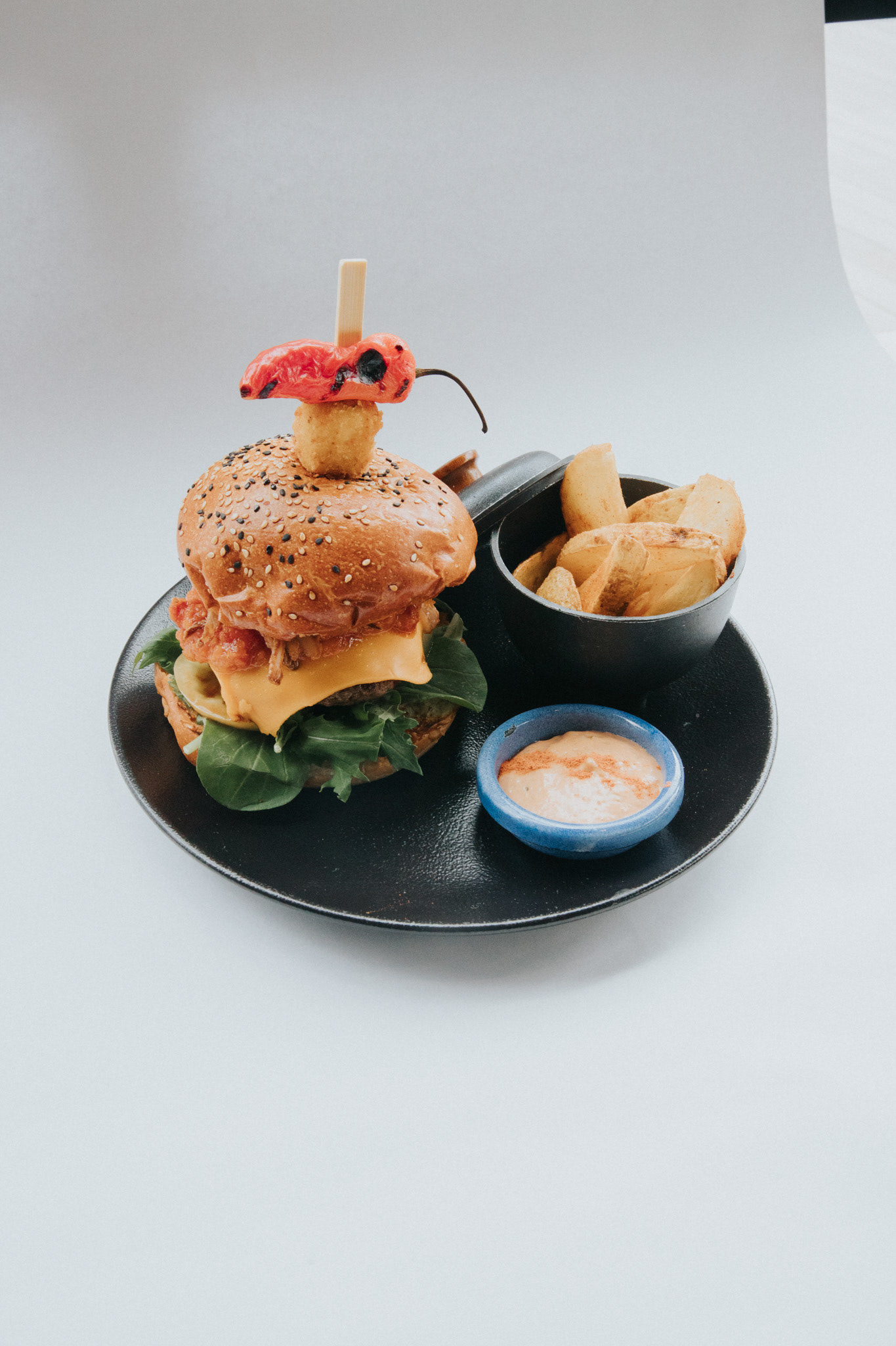 Hamburguesa de Res Wink de 150 gr con con queso cheddar, cebolla crocante, tocineta, mezclum, salsa de la casa y mermelada tocineta, acompañada de papas al romero