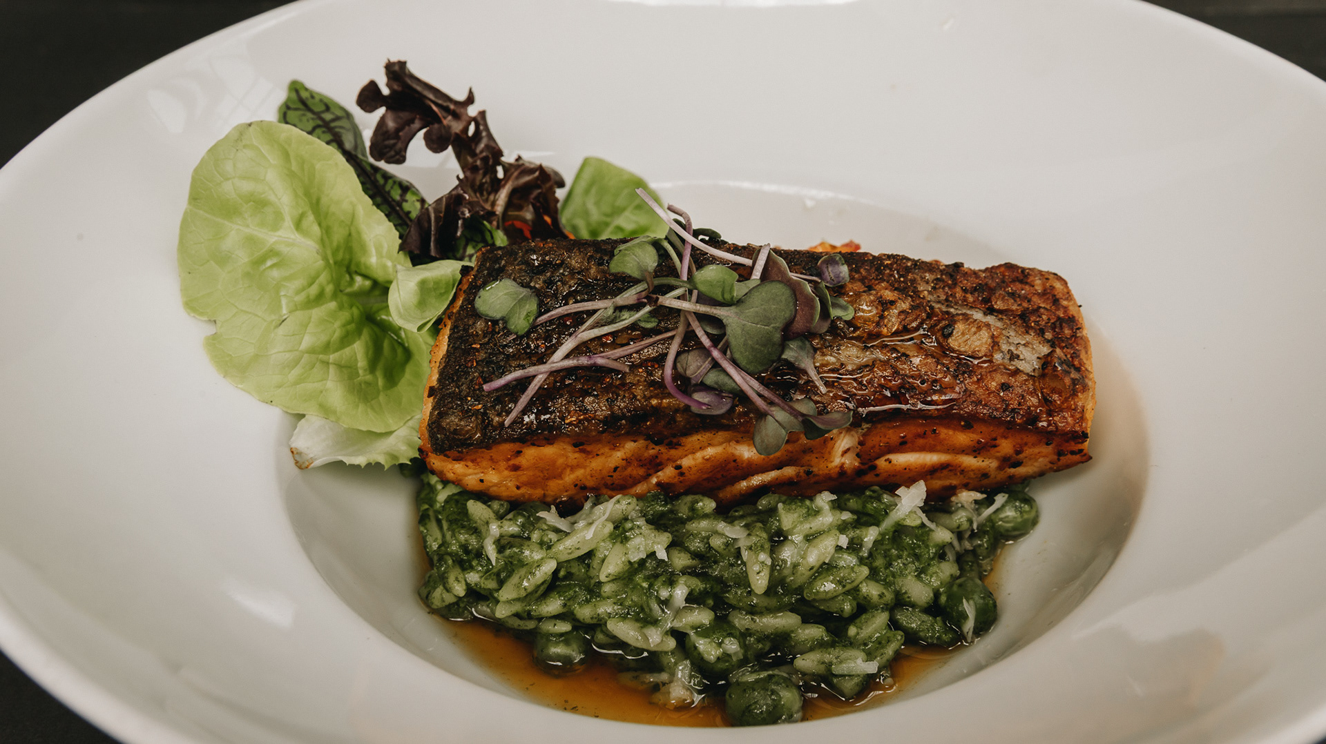 Salmón con Salsa de Cítricos, Pasta Orzo con Espinaca Bogotana, Tomate Cherry Rostizado, Vegetales Baby y Brotes de Temporada