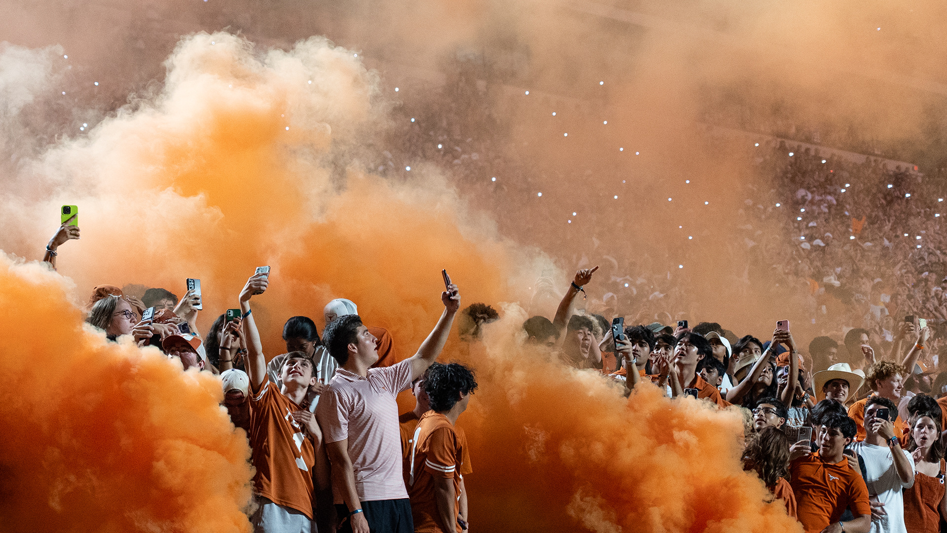 Texas students film themselves on mobile phones as burnt orange smoke fills the air in between the third and fourth quarters of a game versus the Wyoming Cowboys at Darrell K Royal-Texas Memorial Stadium in Austin, TX, Saturday, Sep. 16, 2023.