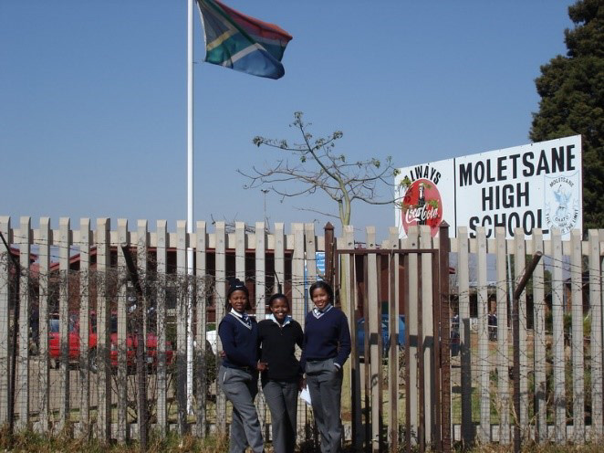 Figure 2: Students pose in front of a barbed wire fence outside Moletsane High School (Ismail Farouk via Flickr)
