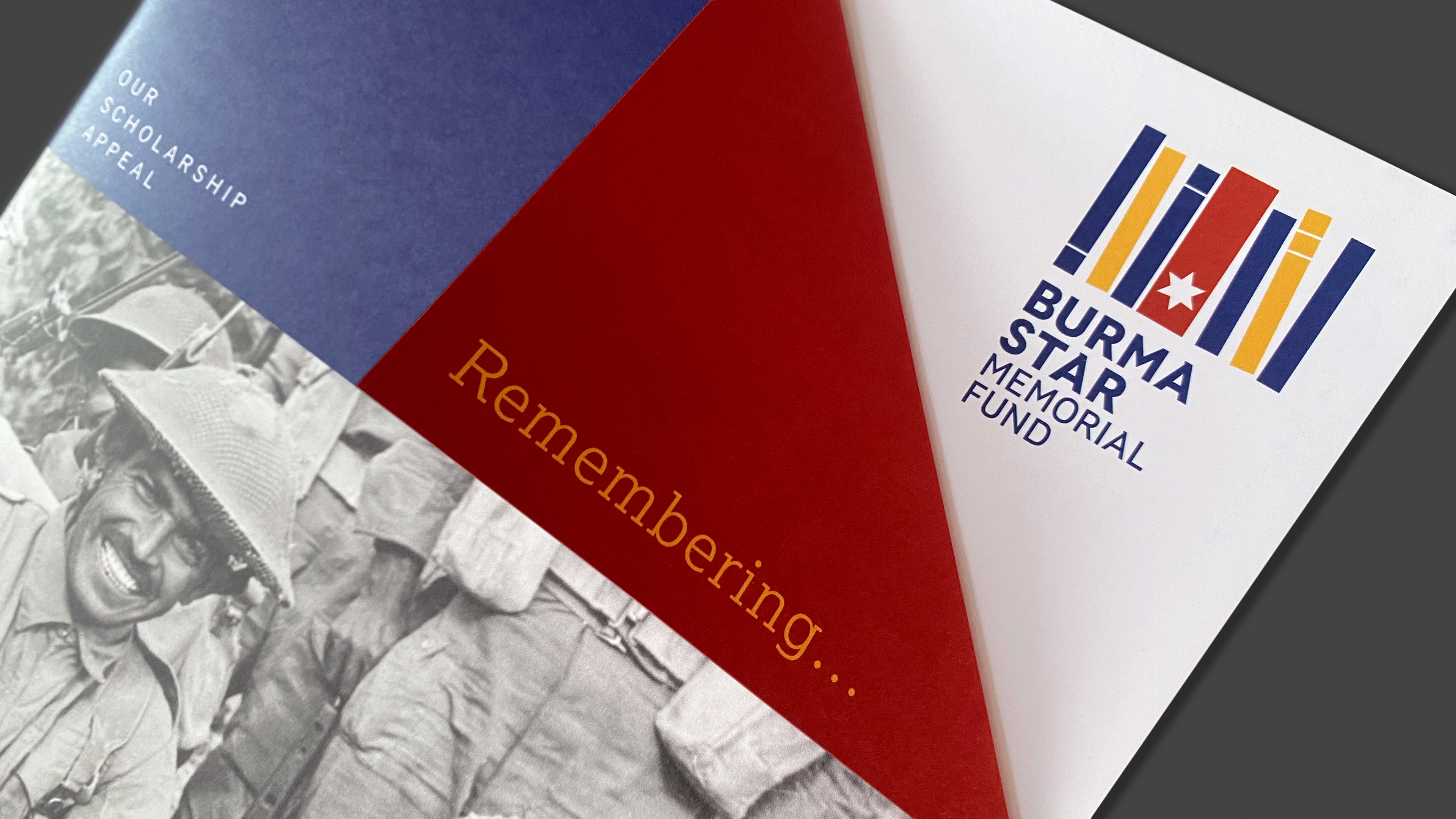 Front cover of the Burma Star Memorial Fund Scholarship Appeal brochure titled 'Remembering the Forgotten Army'. The corner of the brochure cover  is folded over as an aide memoire. 'Remembering...' is visible to the viewer while the rest of the title is revealed underneath the fold. 
