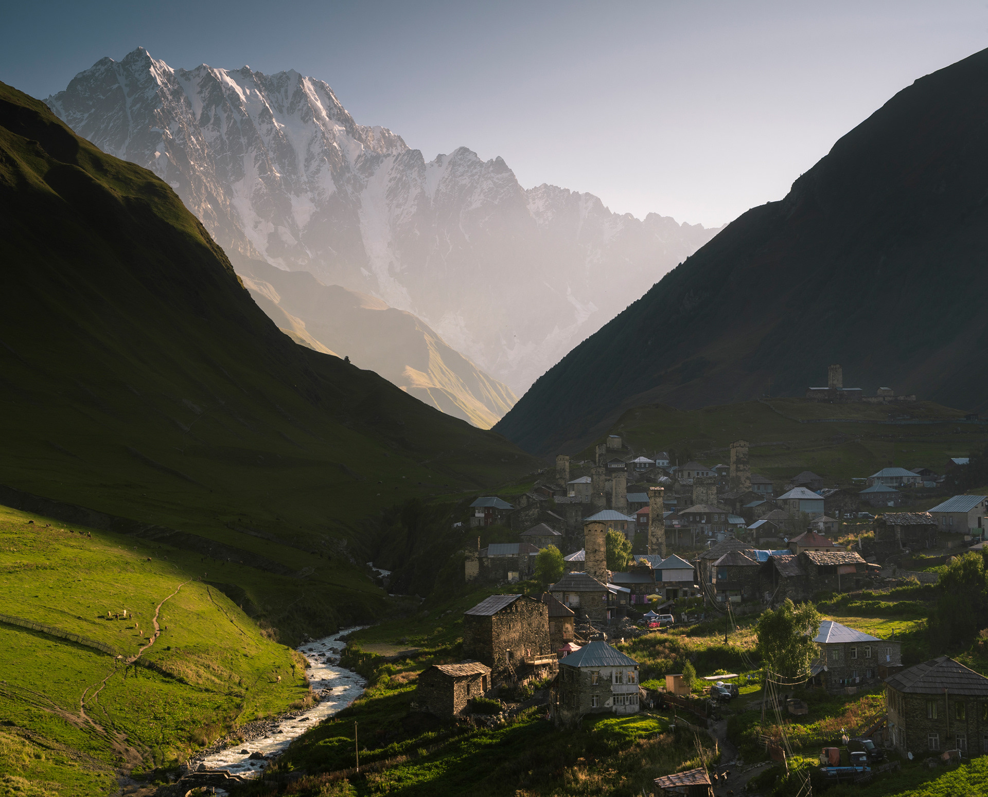 A sunrise over a mountainous village, with ancient defensive stone towers.