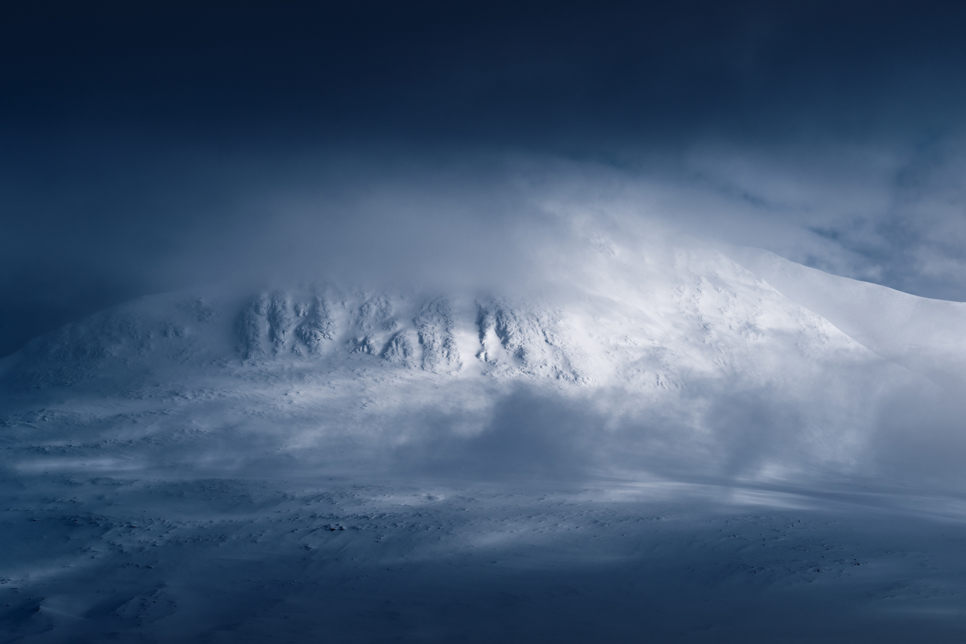 A snowy mountain emerges from the stormy clouds, Ahkka, Stoja Sjofallet / Sarek, Swedish Arctic. Winter landscape.
