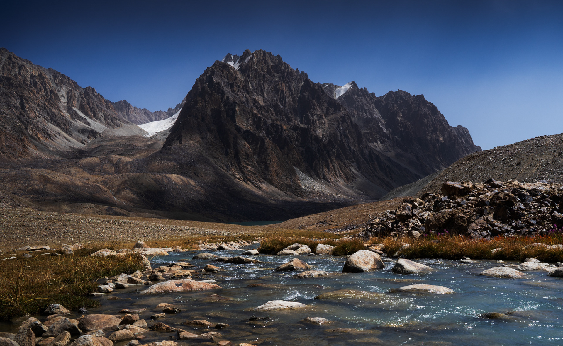 A landscape with jagged peaks and a river in the foreground.
