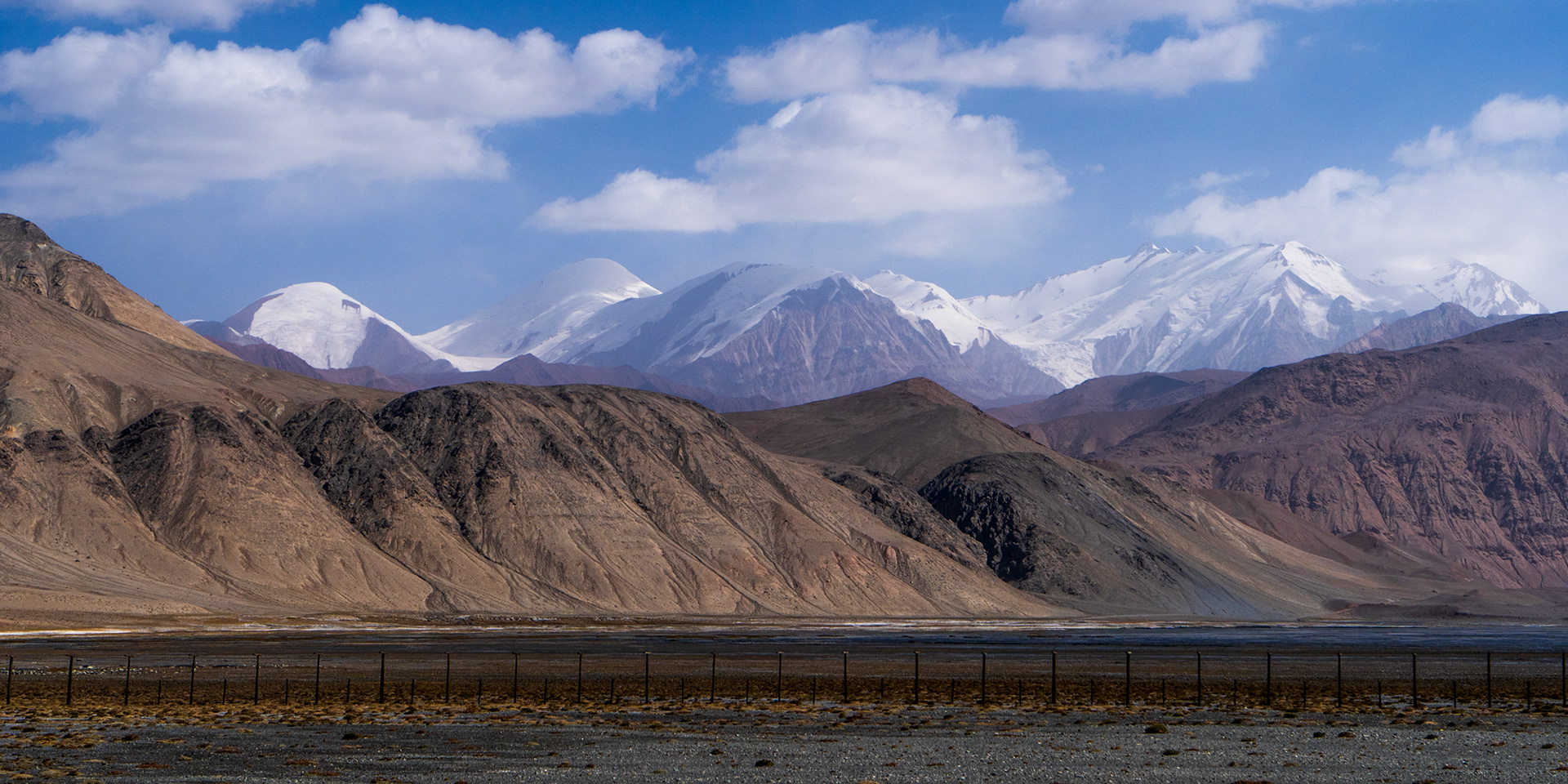 A border fence and snowy mountains in Pamir.