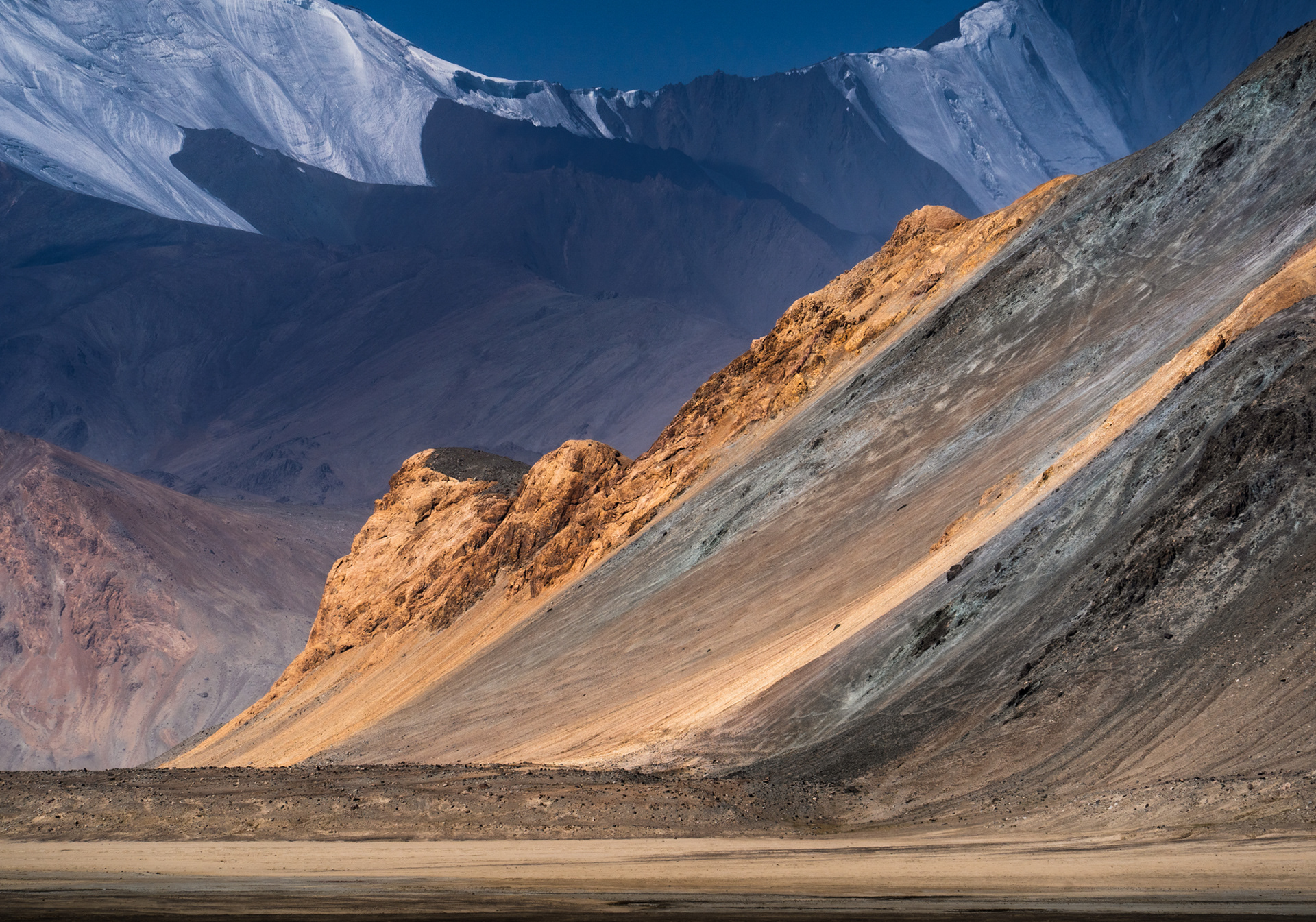 Sun hitting coloured and layered mountains in Pamir.