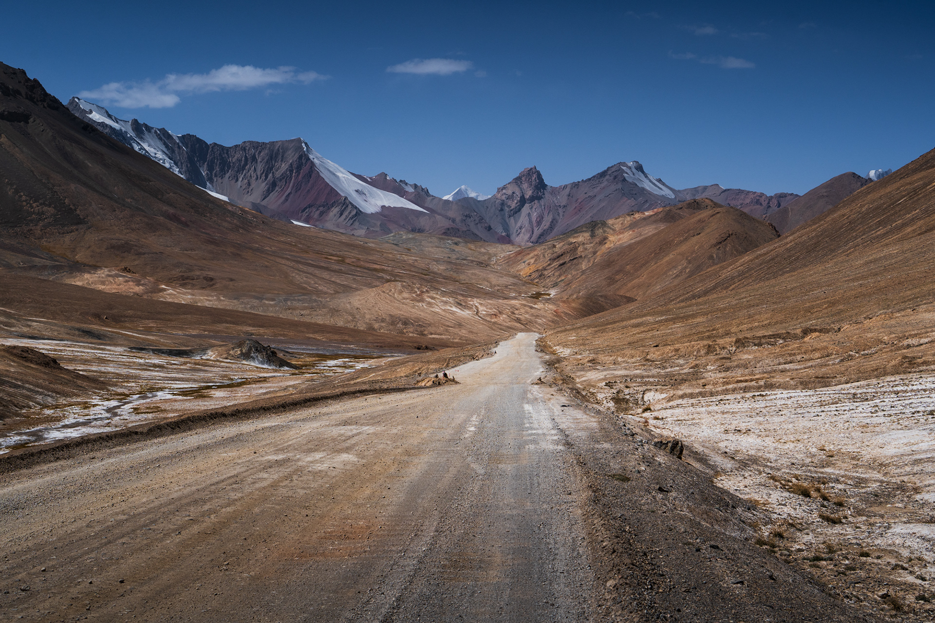 A rugged road through a barren, mountainous landscape in Tajikistan.