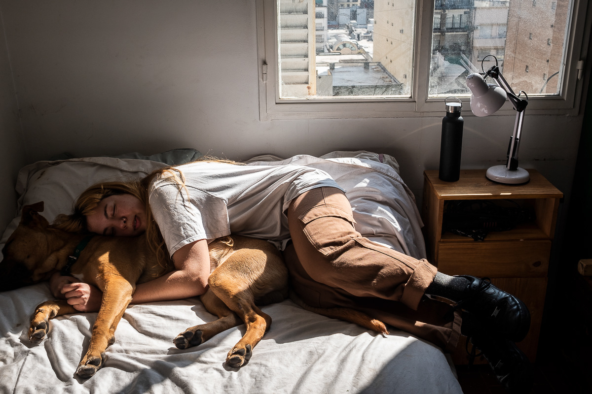 Life story. My friend Candela let me accompany her to see how she lives her life. She works in culture, militates in culture, paints what she doesn't want to forget and dreams of moving to the south. She lives with her sister Sol and her dog Ramón in an apartment in Buenos Aires that is full of beautiful light. The apartment has a good orientation, I guess west where the sun sets. The light filters through every hole, floods the shadows and at about seven o'clock in the evening tints everything in a different color. Just before it hides completely.