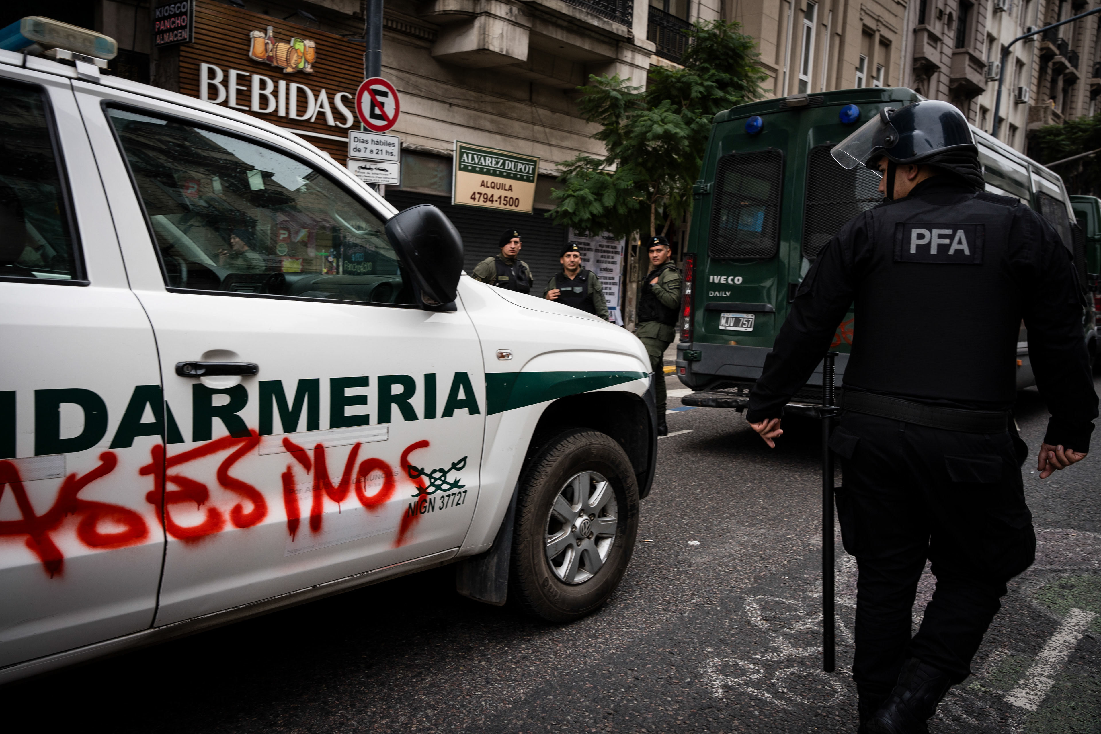 A policeman looks at graffiti on a gendarmerie car with the words "Murderers". The Senate Chamber of the Argentine Congress is debating Javier Milei's Ley Bases, which has already passed the Chamber of Deputies. Meanwhile, hundreds of thousands of demonstrators are protesting in the streets, leading to confrontations and repressive actions by security forces, in Buenos Aires, Argentina, on June 12, 2024. PHOTO: Santiago Oroz