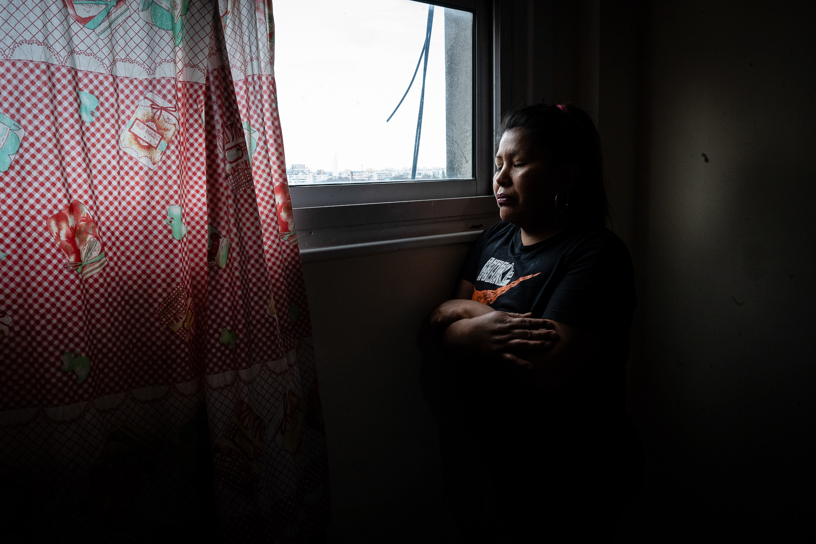 Aide Flor Rojas Quispe in front of the window of her apartment located in the building at Santa Cruz 140, waiting for the imminent eviction that the police have planned for her home the next day, in the neighborhood of Parque Patricios, Buenos Aires, Argentina, on October 30, 2023. PHOTO/Santi Oroz.