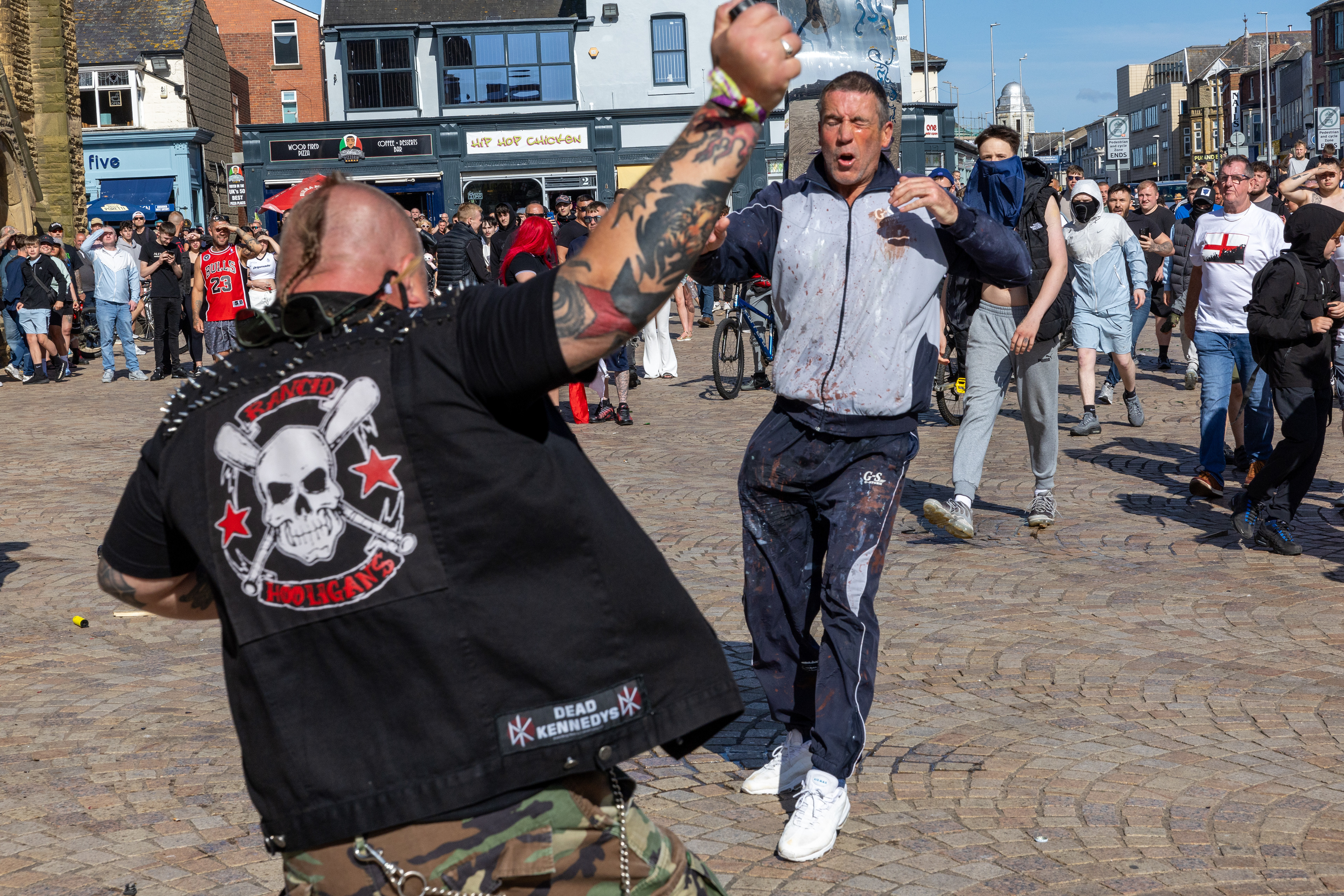 A man, left, falls backwards after a brief fight with another man in Blackpool town centre on Saturday August 3 2024. The man hit his head on the ground and suffered a broken skull and bleed on the brain