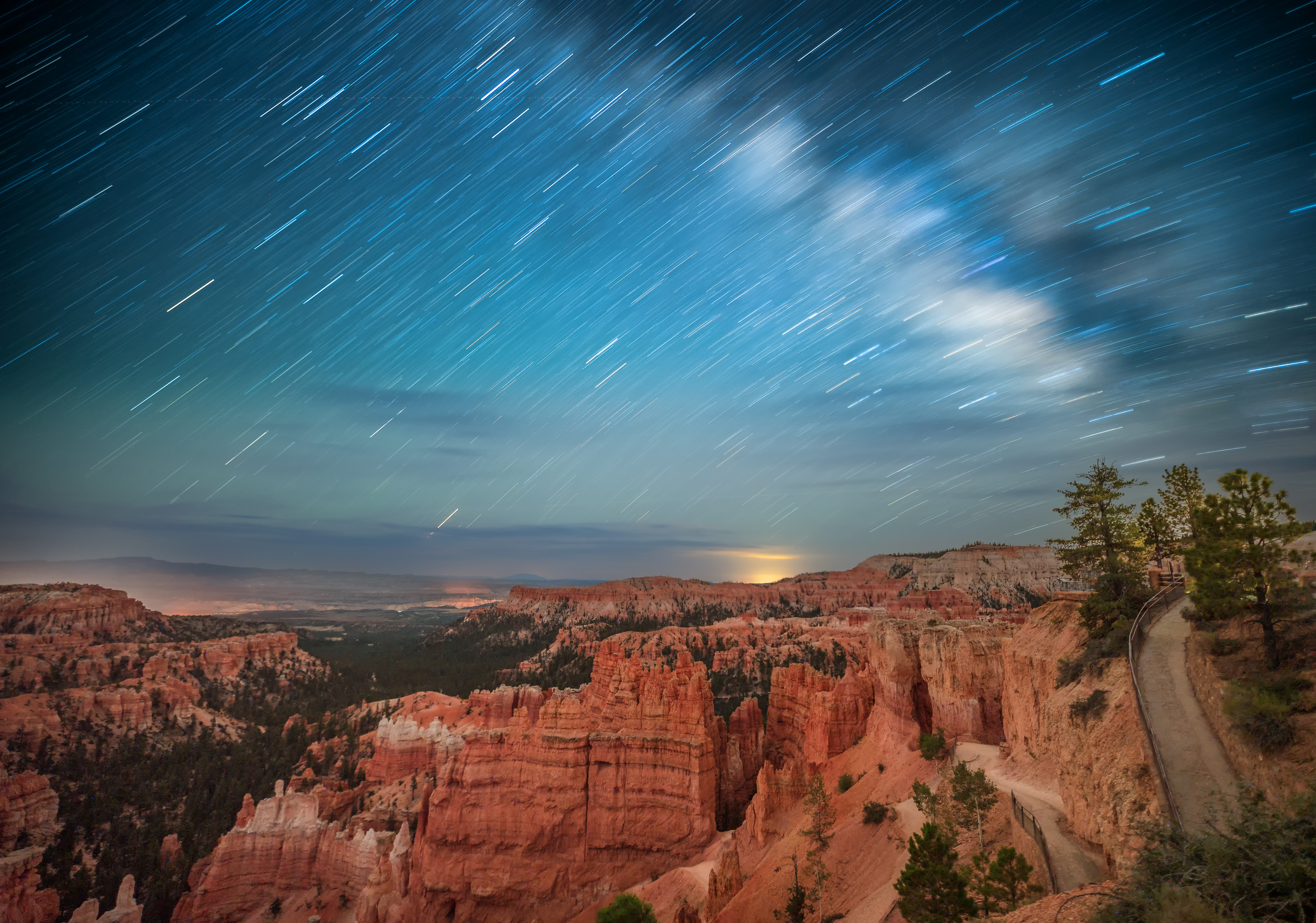 "Starry skies over Bryce Canyon"  Hoodoos are quite a unique spectacle when lit up by the night sky. The colour which shines off from the starry Night Skies is such a unique spectacle to watch late at night. After exploring the canyon floor trail I found an ideal spot for astro in the evening. Having a view of this many Hoodoos lit up by night was a bucket list shot of mine, to get a daytime like photo in the pitch black.  Going back through my archives I decided that this photo needed a good edit, when it was last posted it was a stock photograph and I felt that going through and taking the time (at the time I was travelling) to create a much more colourful and interesting image would be fun. Those satellites look quite cool as well! 