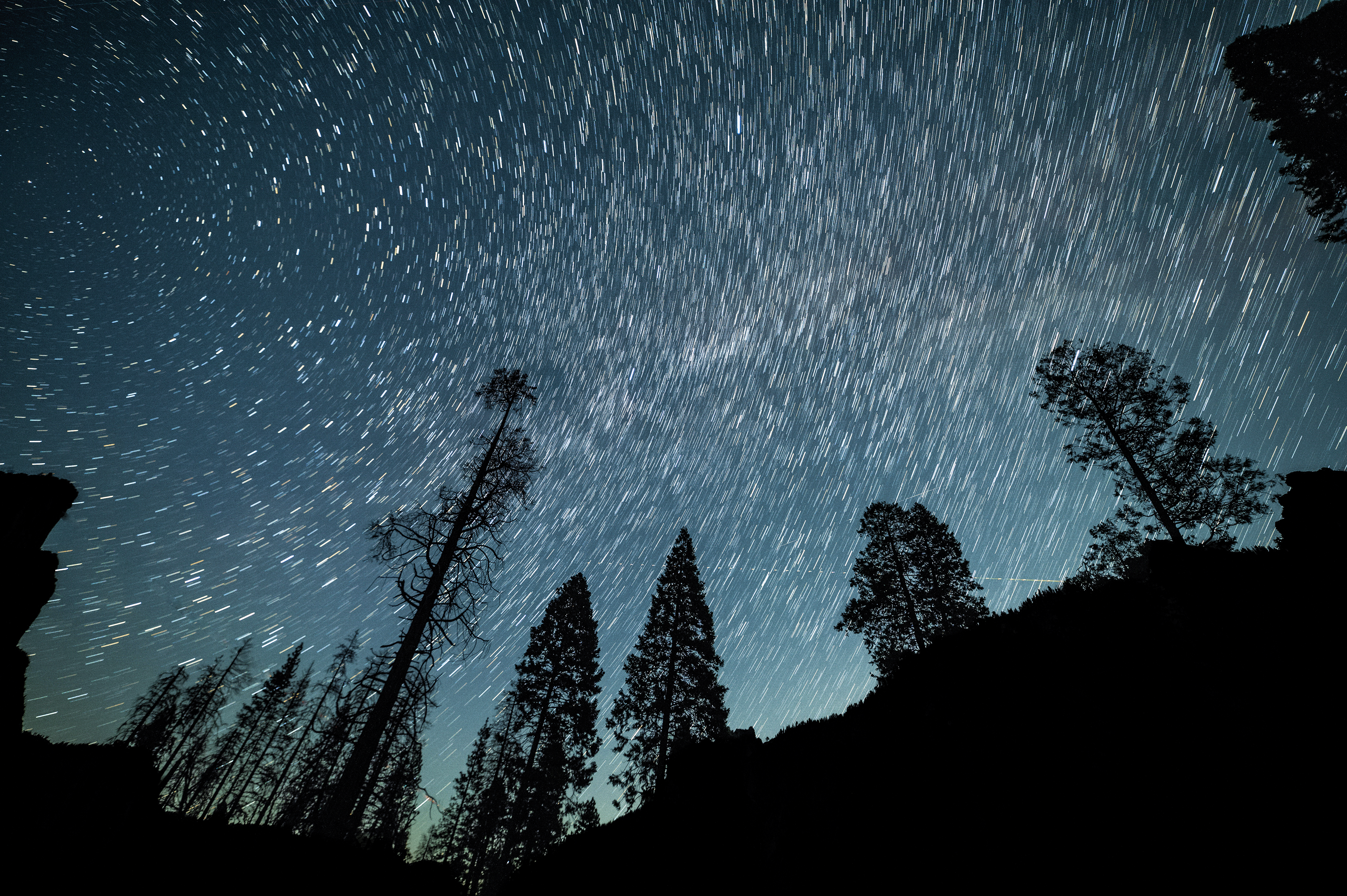 "Three Brother Peaks by night in Yosemite Valley"  Travelling through Yosemite Valley at night gave some incredible spectacles, the colour of the sky pierced through the pitch black undergrowth as me and my dad tried to find a perfect spot to start some astrophotography.  The previous weeks had been incredibly bad visibility, with forest fires spreading further into the valley. Luckily there was a small break in conditions for 2 days before worsening, luckily this is when we visited! This meant I had a incredible opportunity to start some astrophotography, even if I was way to jet lagged.  This was the first Astro image I have taken outside of the UK and it was a very special moment for me, the silhouette of pine trees with the Three Brother Peaks off in the distance created the perfect composition for a classic astrophotography shot. I am still obsessed with changing style of star trails, going for shorter exposures as I've figured out can give a much more subtle effect to the image, and a lot less punchy than the longer ones I've completed.