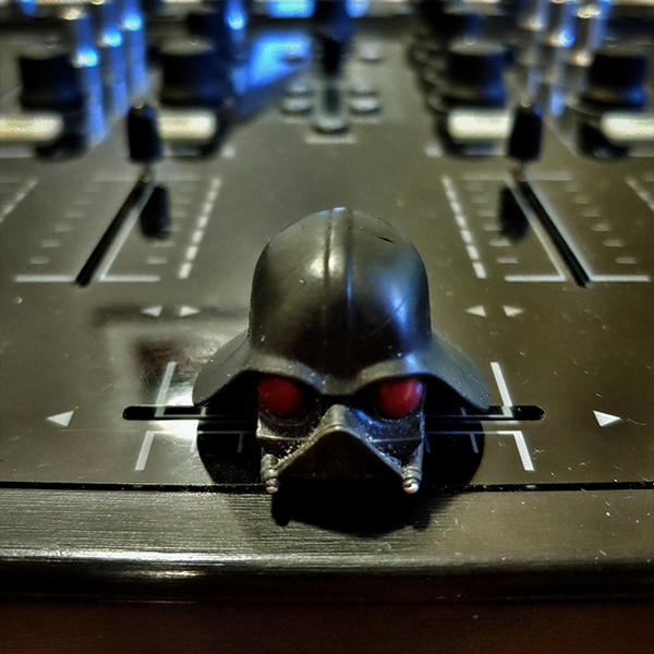 A close up shot of a cross fader on a DJ controller, however the fader slider is a Darth Vader helmet, making it a Darth Fader