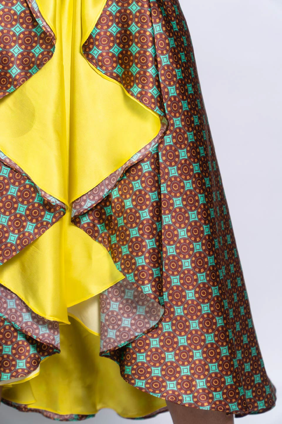detalle de parte inferior de vestido estampado con diseño de inspiración africana en colores turquesa, bordeaux y amarillo