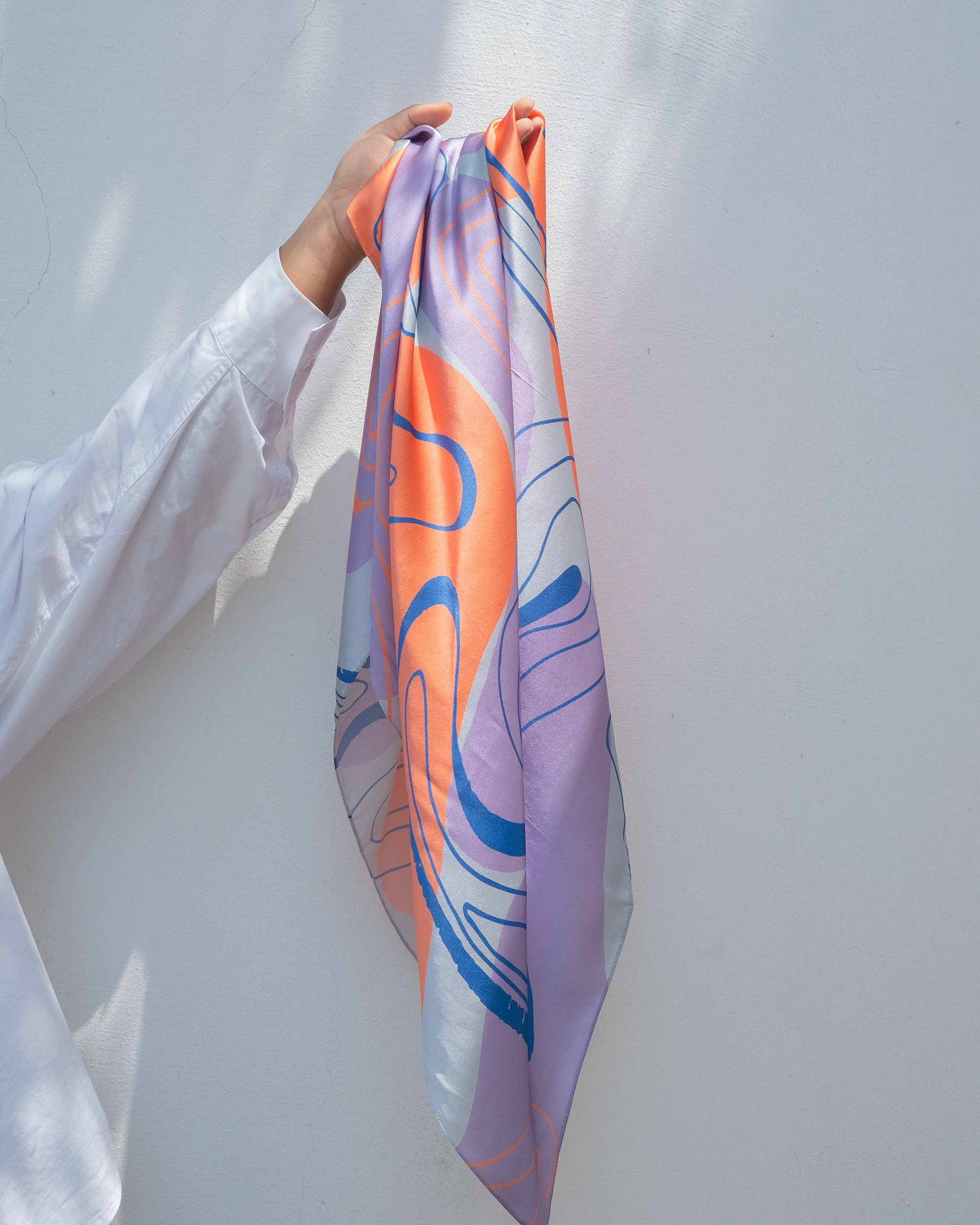 pañuelo de seda estampado colgando de la mano de una mujer