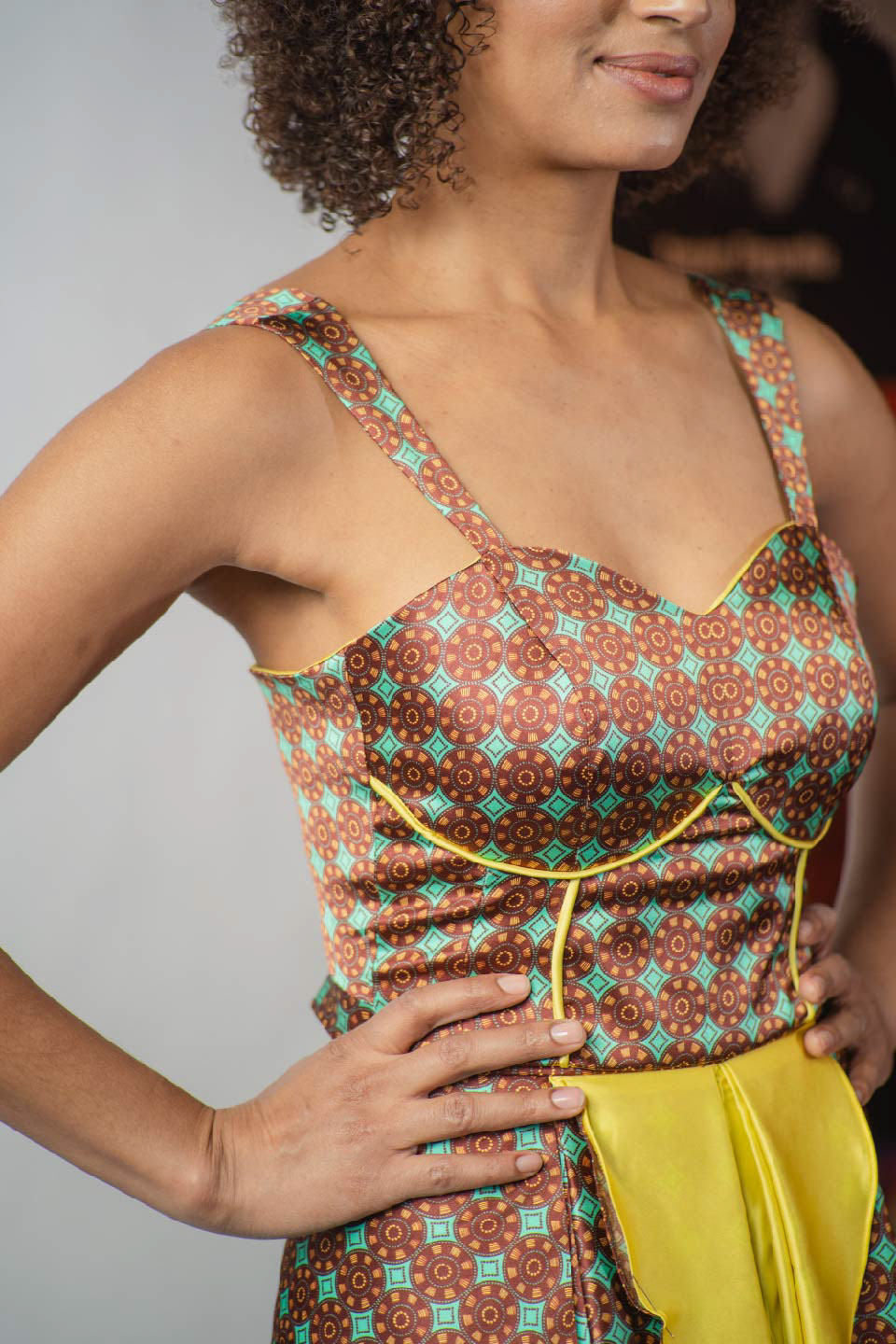 detalle de parte superior de vestido estampado con diseño de inspiración africana en colores turquesa, bordeaux y amarillo