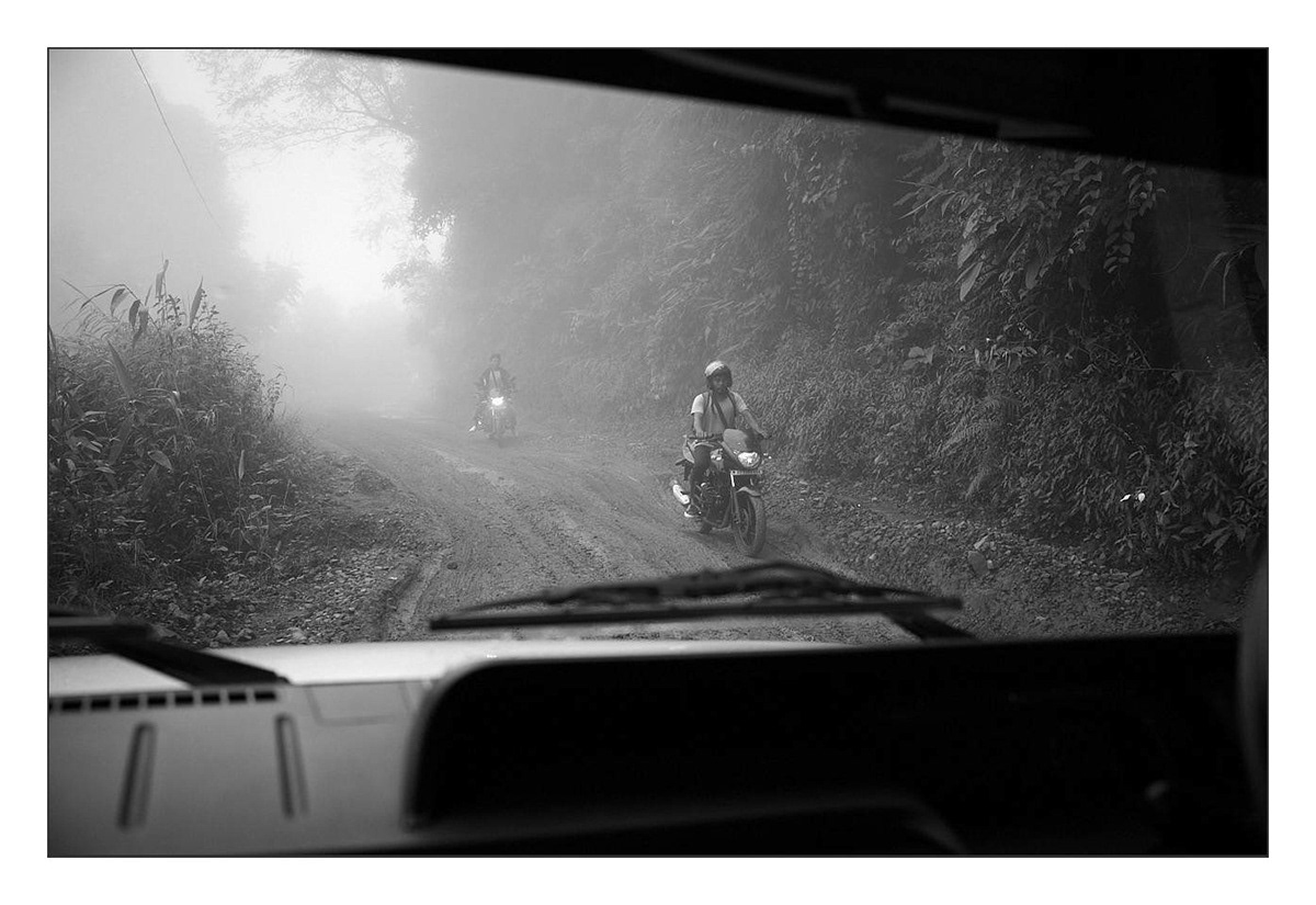 Motorcyclists descending the muddy road from Mon